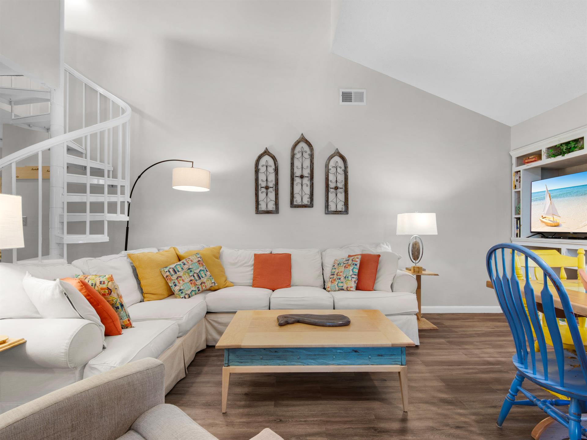 Sink into your spacious sectional sofa and unwind in this bright, airy living room with soaring ceilings and vibrant coastal touches.