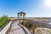 Wooden boardwalk leads to a charming gazebo overlooking pristine beach dunes and ocean views.