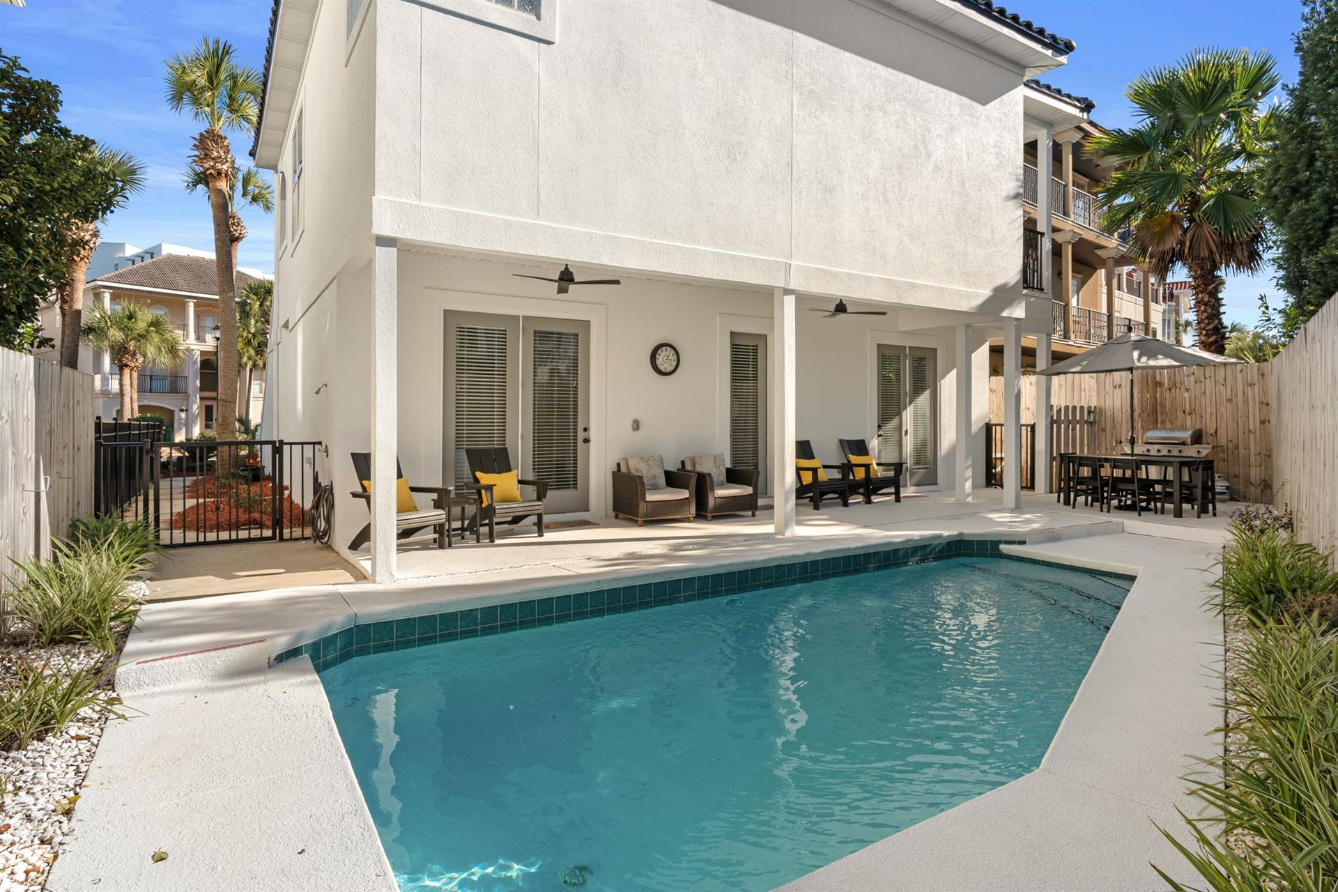 Your private pool paradise awaits with covered patio seating and tropical palms creating the perfect retreat.