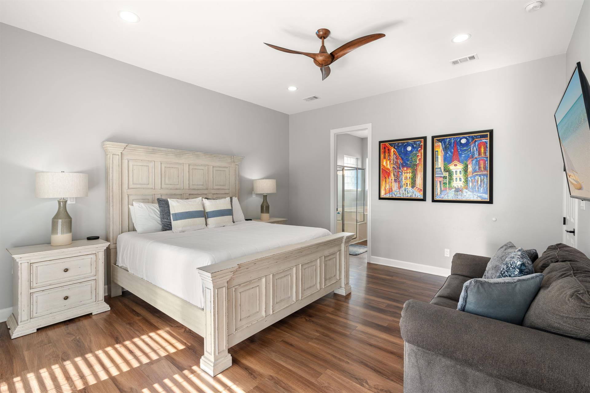 Bedroom 1 featuring a plush king bed, cozy seating area, and elegant coastal artwork that creates the perfect retreat.