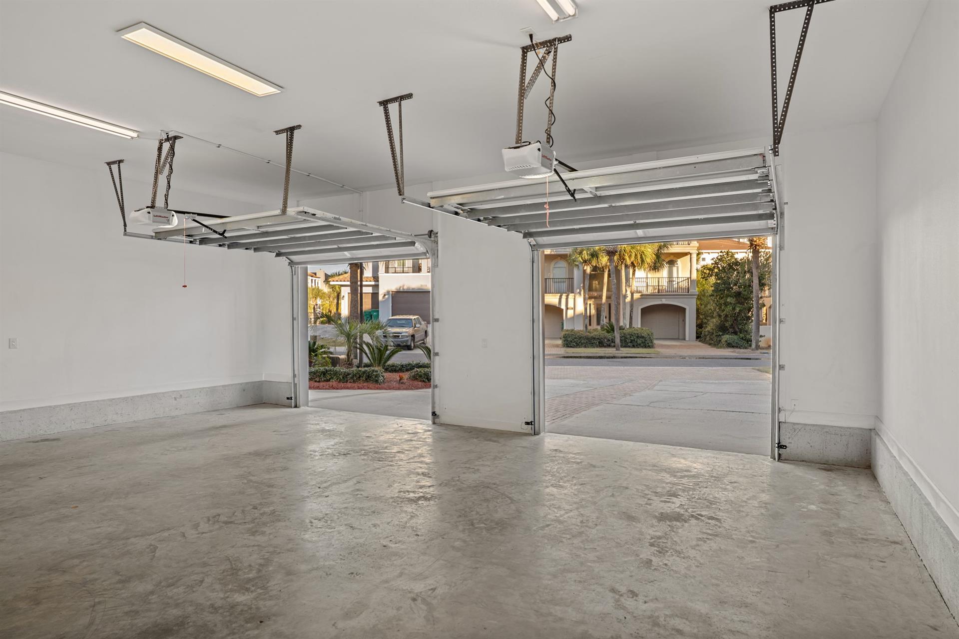Spacious twocar garage with automatic doors opens to a quiet residential street lined with elegant homes and mature landscaping.