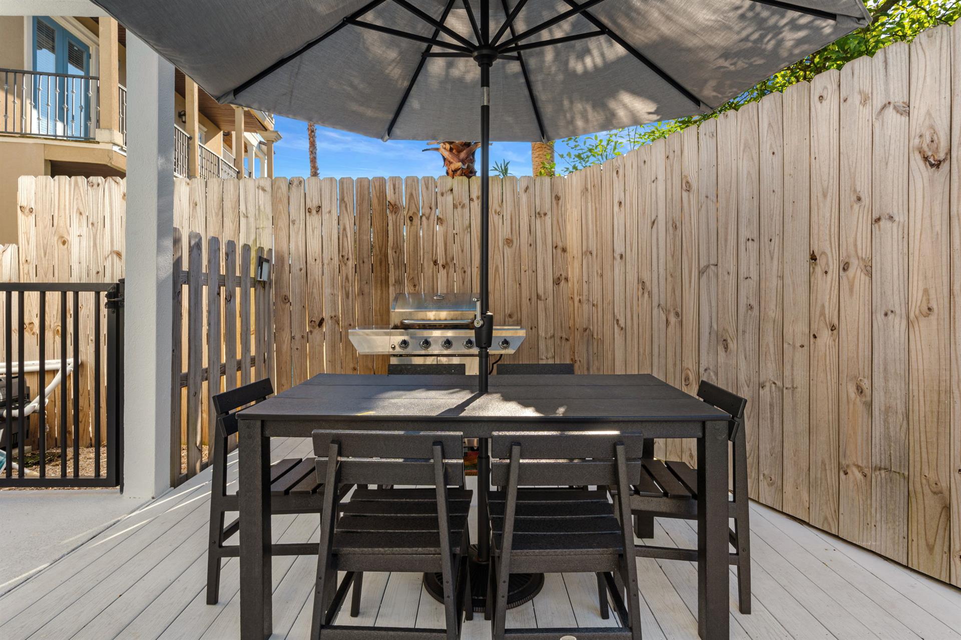 Your private patio awaits with dining table, umbrella shade, and BBQ grill ready for memorable outdoor meals and relaxation.