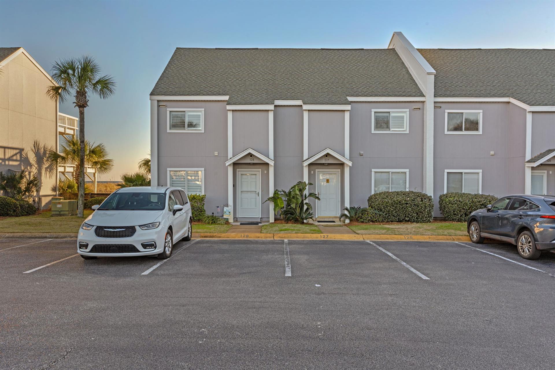 Twostory property building with convenient parking spaces directly outside your vacation rental, surrounded by tropical palm trees and landscaping.