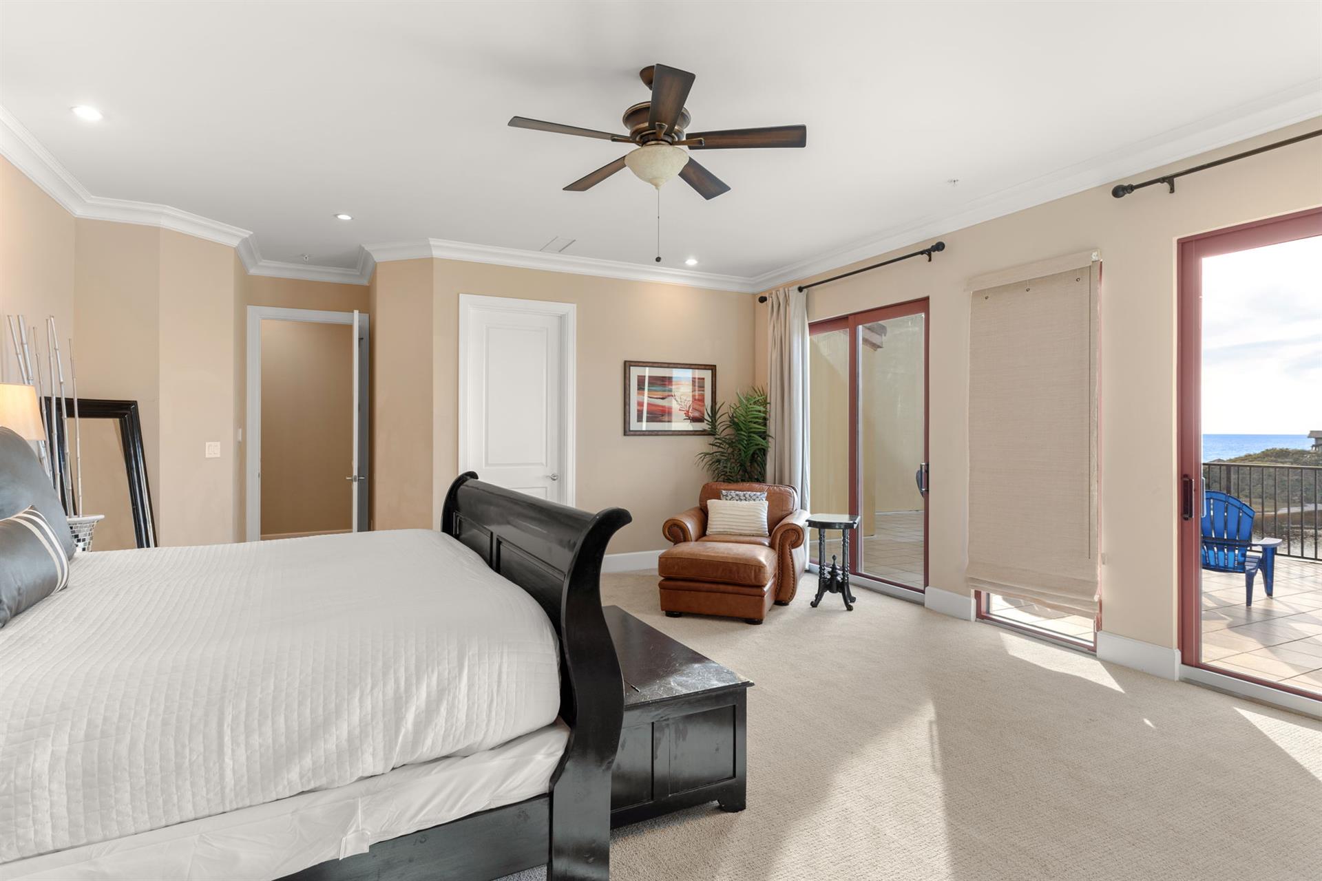 Relax in your spacious bedroom with plush carpeting, ceiling fan, and private balcony access offering peaceful outdoor views.