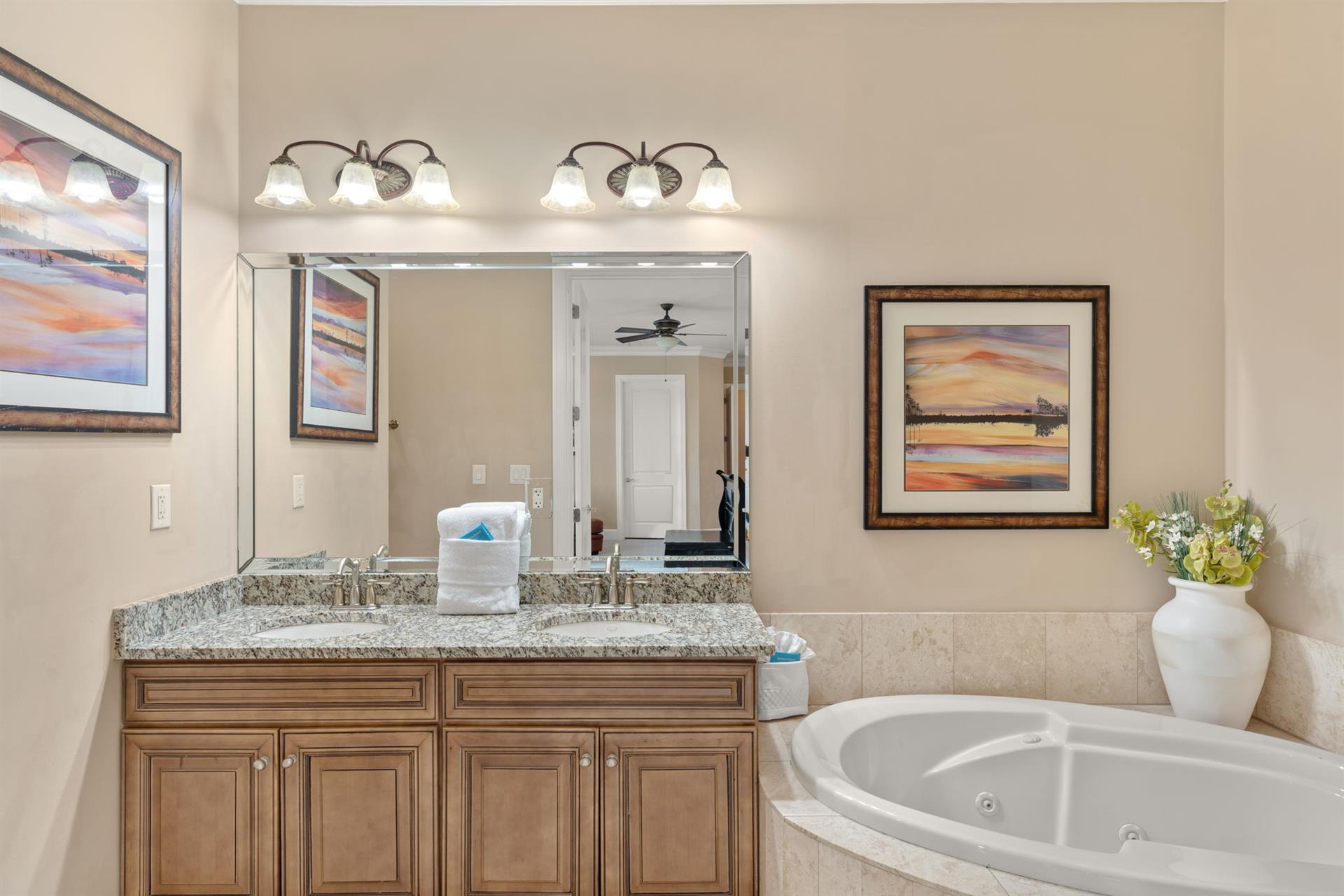 Unwind in your elegant ensuite bathroom featuring granite countertops, a soaking tub, and beautiful artwork creating a spalike retreat.