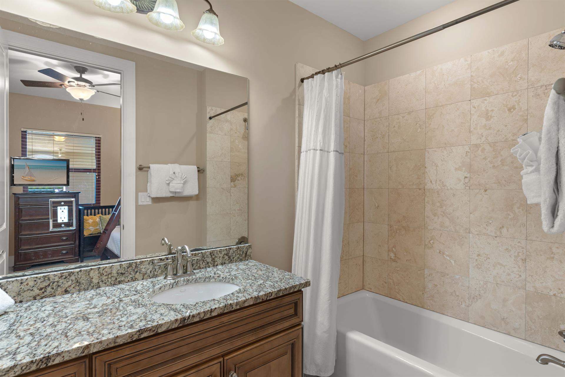 Unwind in your elegant bathroom featuring granite counters, travertine tile, and plush towels for complete relaxation.