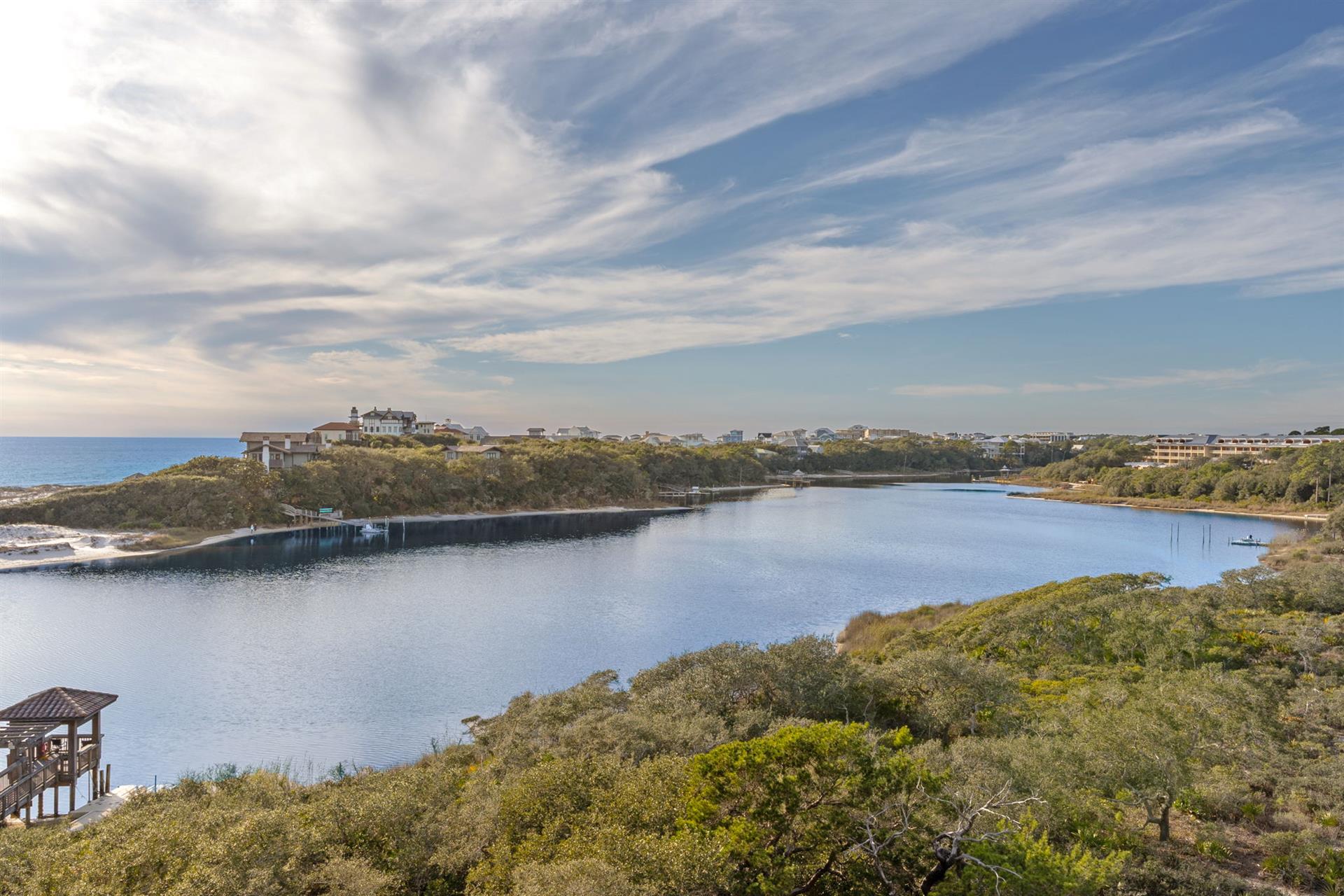 Scenic coastal community with lake, beach access, and charming residential buildings nestled among natural dunes and vegetation.