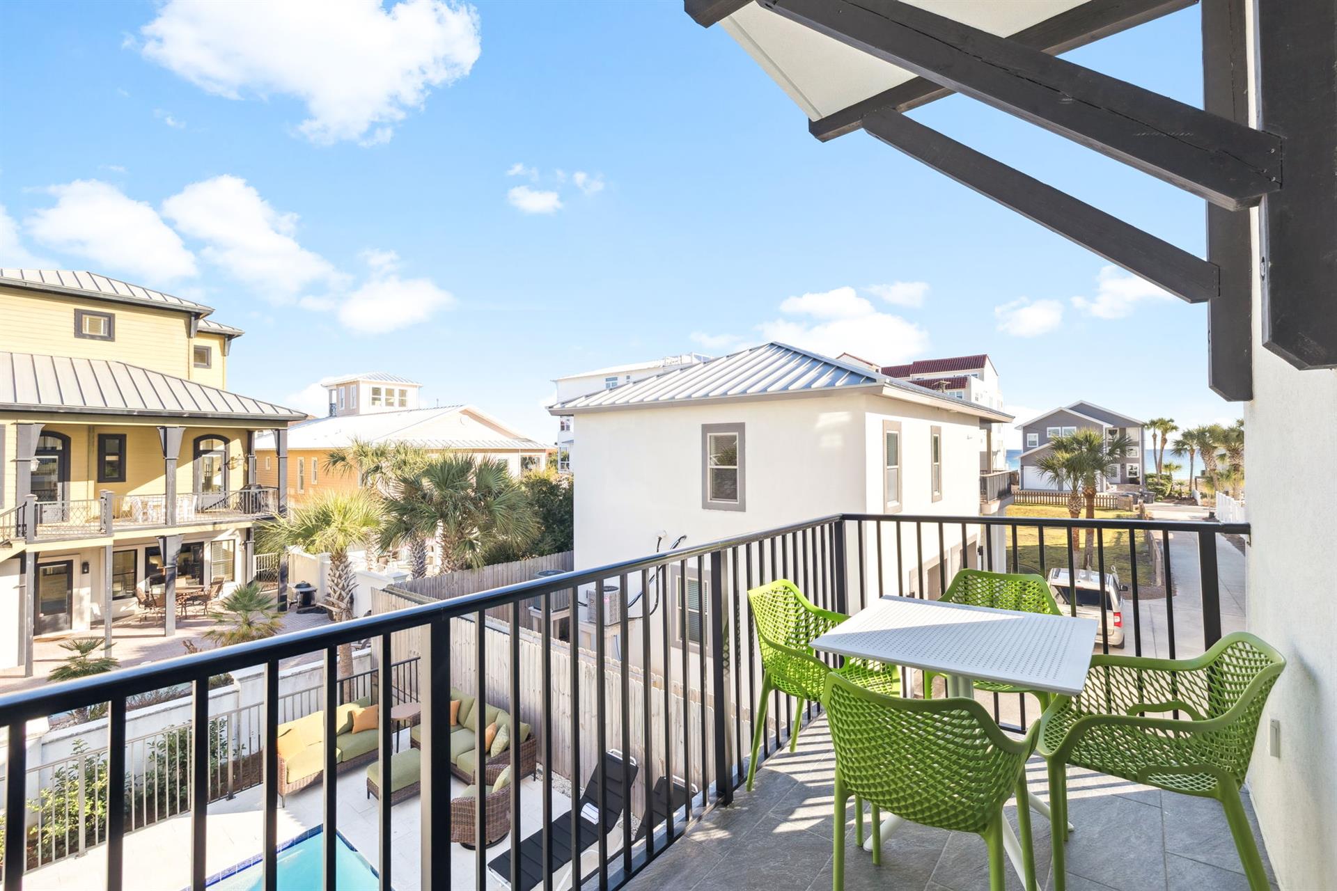 The private balcony offers a perfect spot to enjoy morning coffee while taking in views of the colorful neighborhood rooftops and tropical palms.