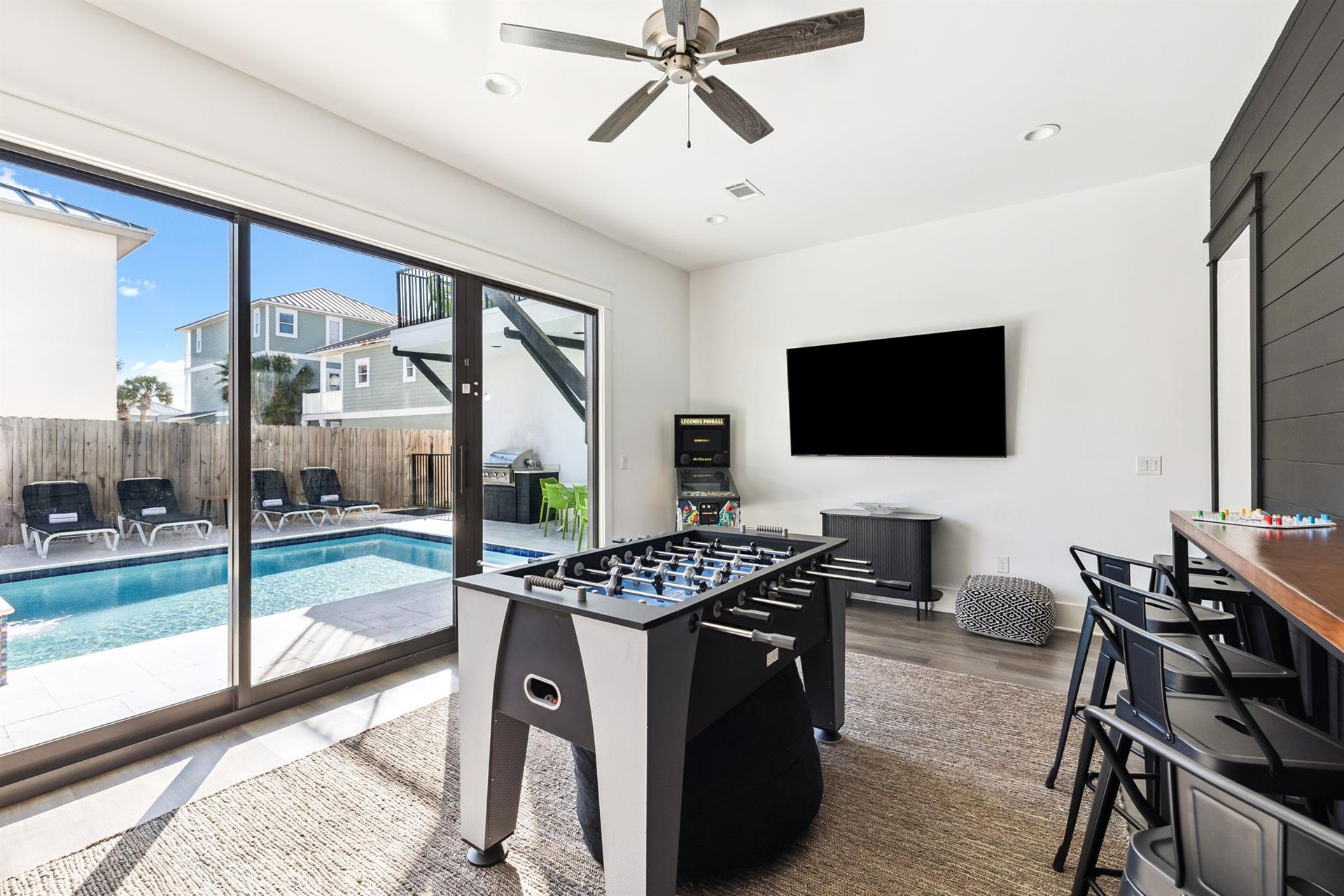 Your entertainment hub opens to a sparkling pool, with foosball, bigscreen TV, and bar seating for endless fun.