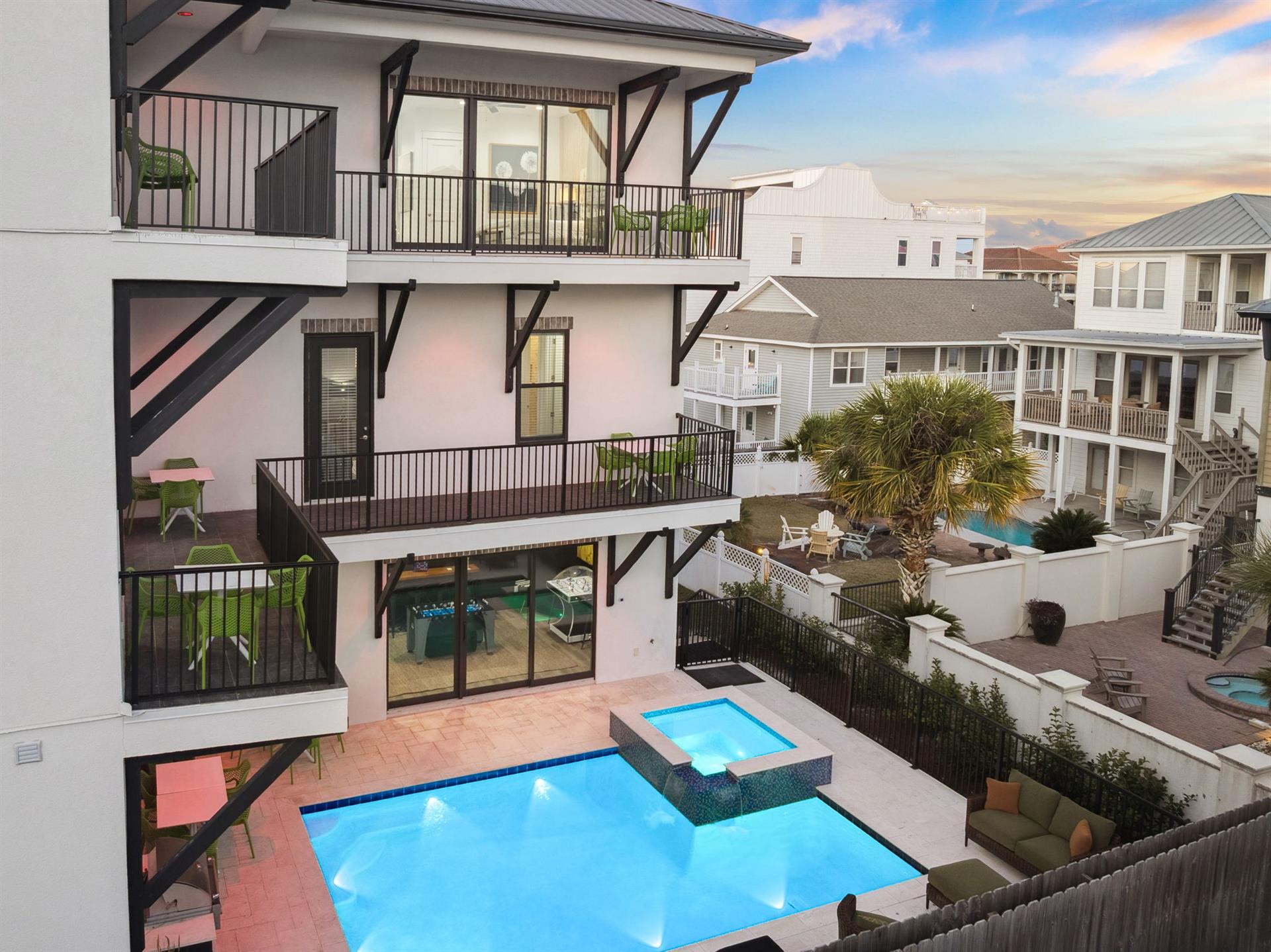 Modern beachside vacation home featuring private pool and hot tub with multilevel balconies in coastal neighborhood setting.