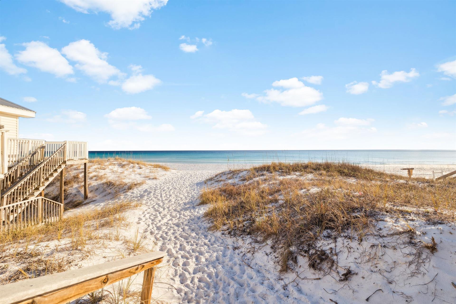 Pristine beach accessible location with direct access to white sand and turquoise waters through natural dunes.