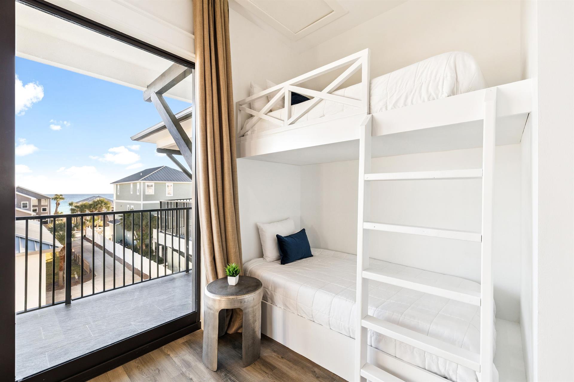 Your modern bunk beds offer comfort and privacy, while large windows flood the space with natural light and balcony access.
