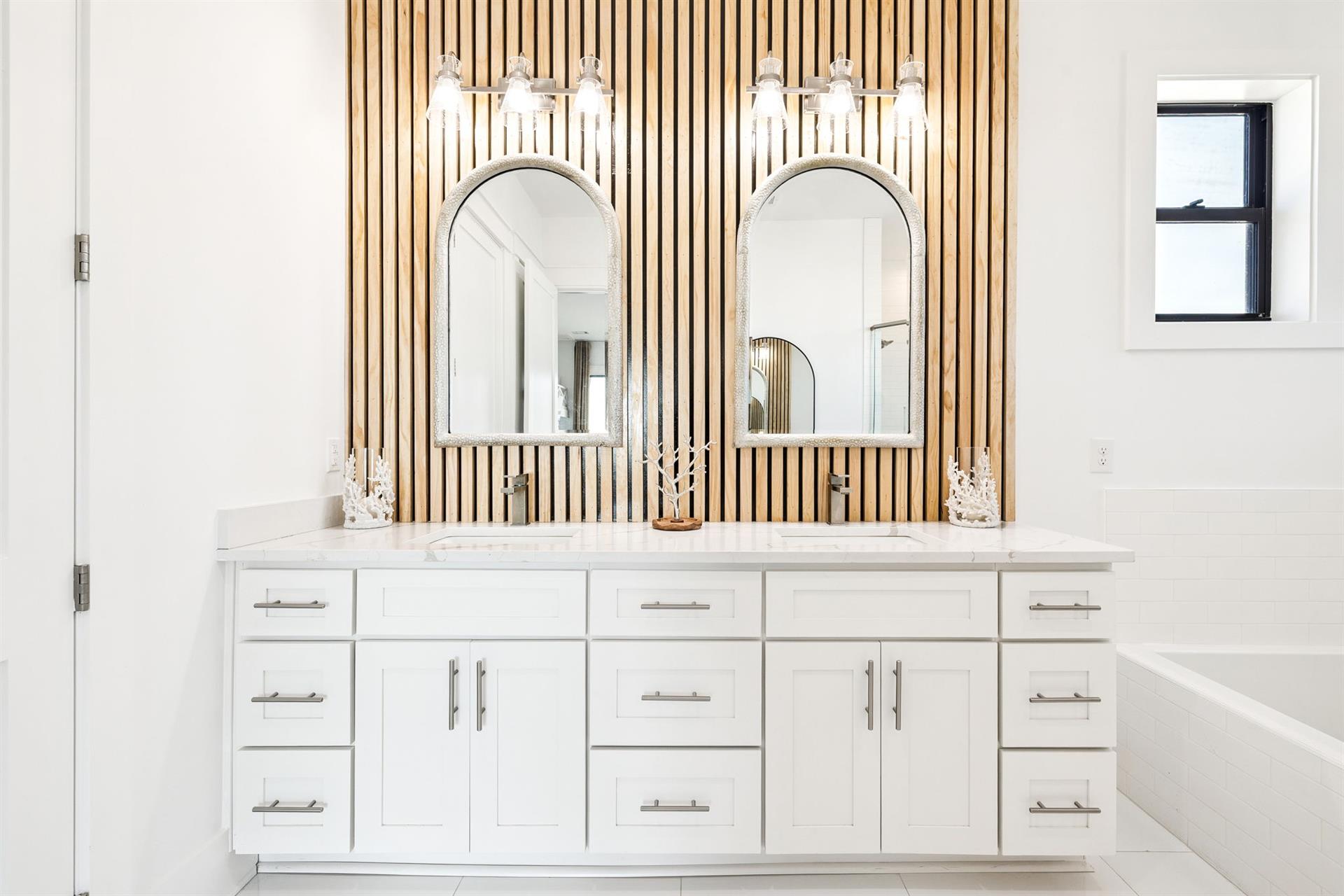 Indulge in luxury at your dualsink vanity with stunning wood slat accent wall and elegant lighting.