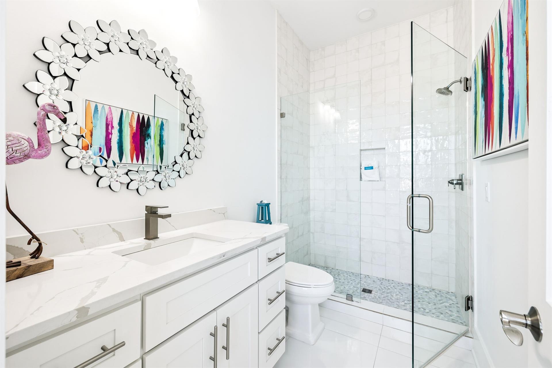 Unwind in your stunning bathroom featuring marble countertops, a glassenclosed shower, and vibrant artwork that adds personality to your private retreat.