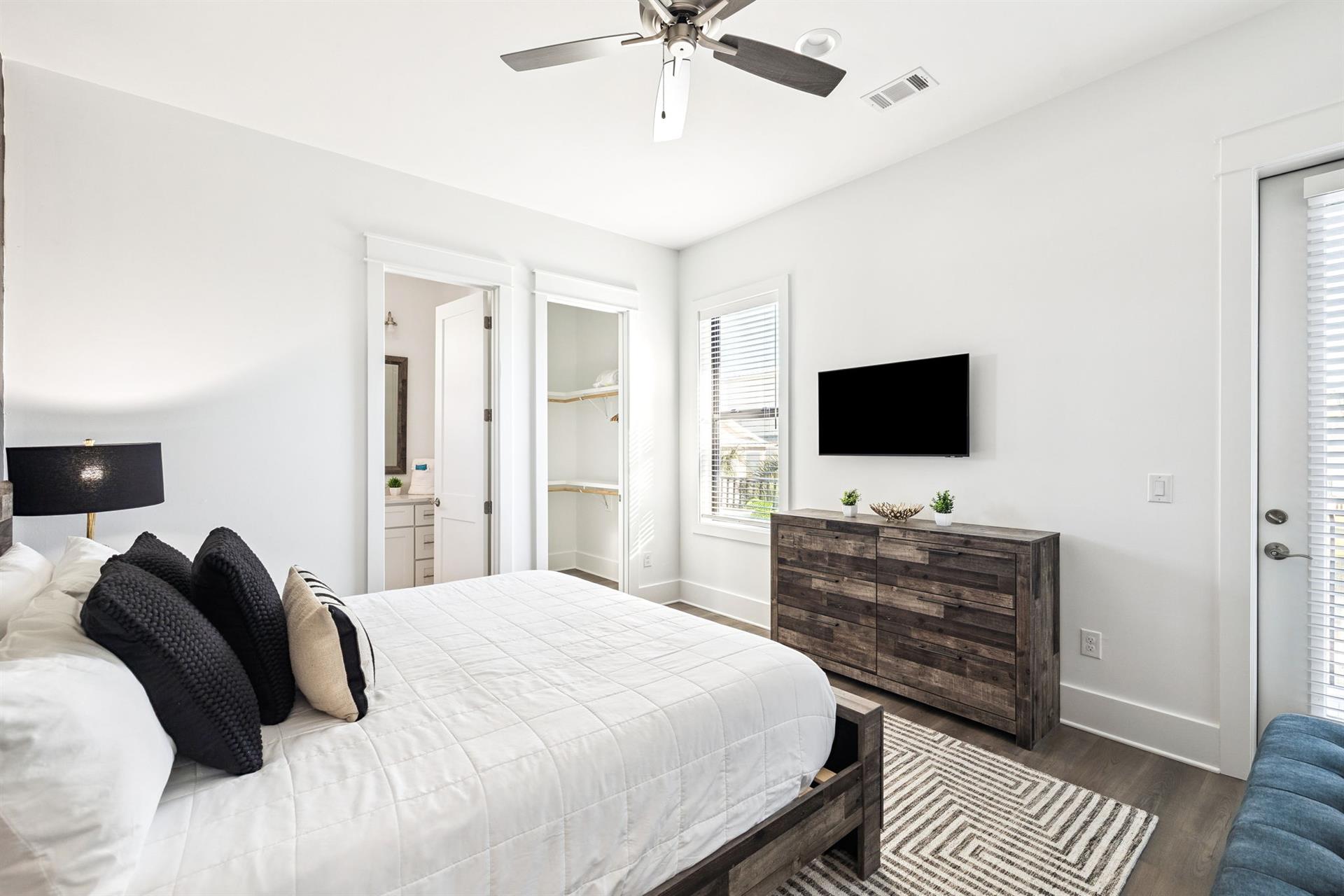 Unwind in your serene bedroom featuring crisp linens, modern furnishings, and a wallmounted TV for cozy evenings.