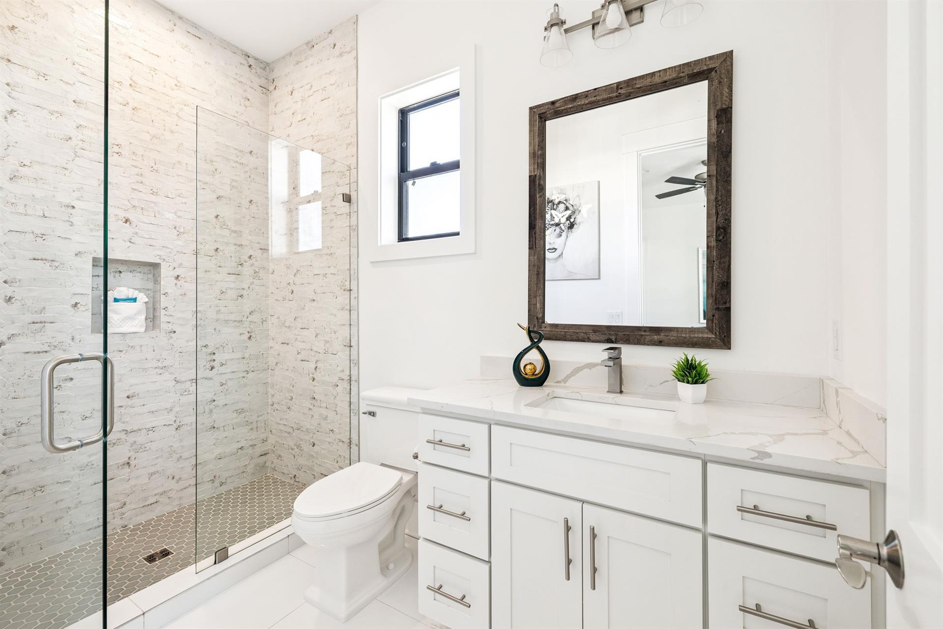 Step into your pristine bathroom where white marble meets exposed brick. The spacious shower and elegant vanity create a perfect morning retreat.
