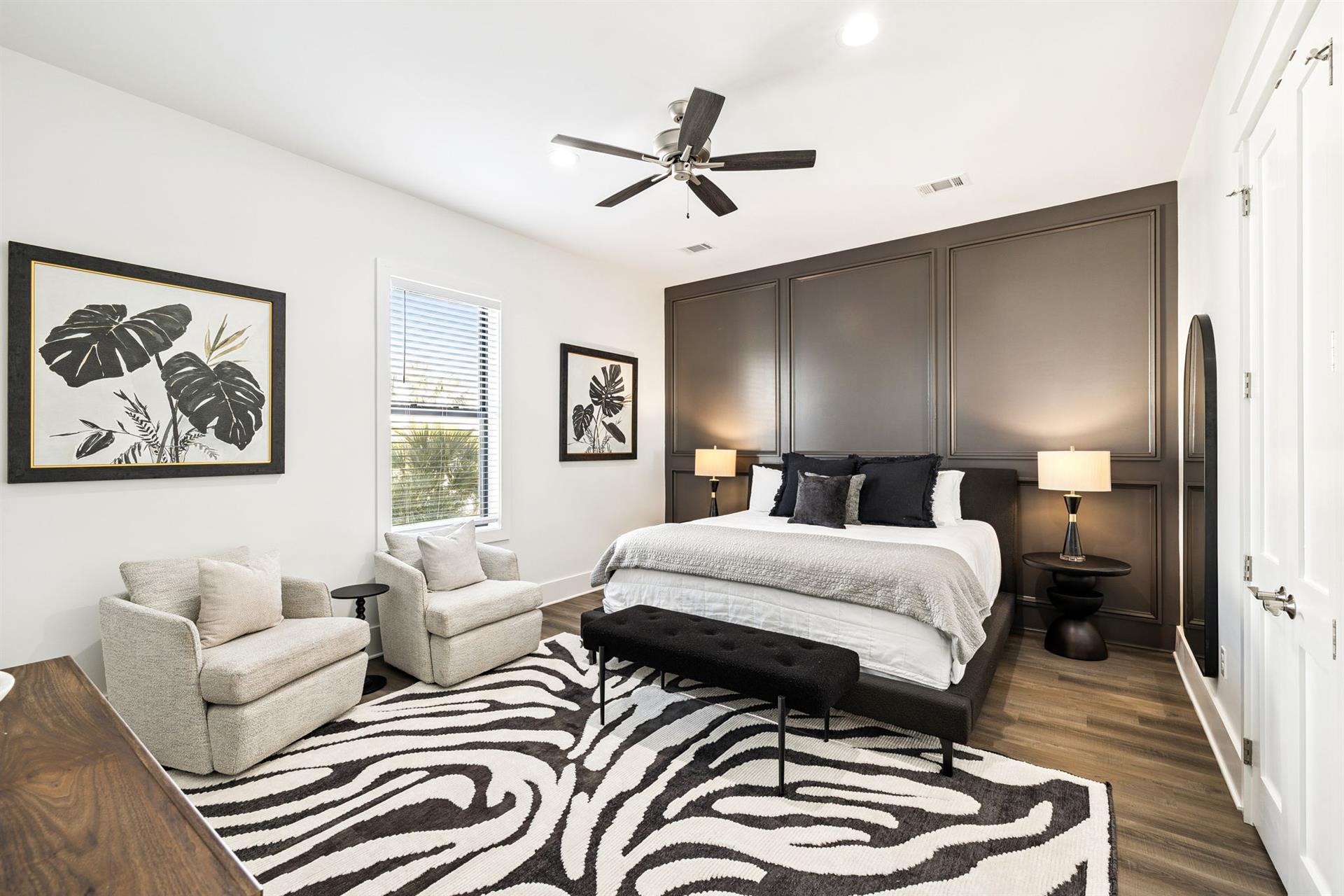 Unwind in your elegant bedroom featuring a cozy seating area and striking zebraprint rug that adds personality to your peaceful retreat.