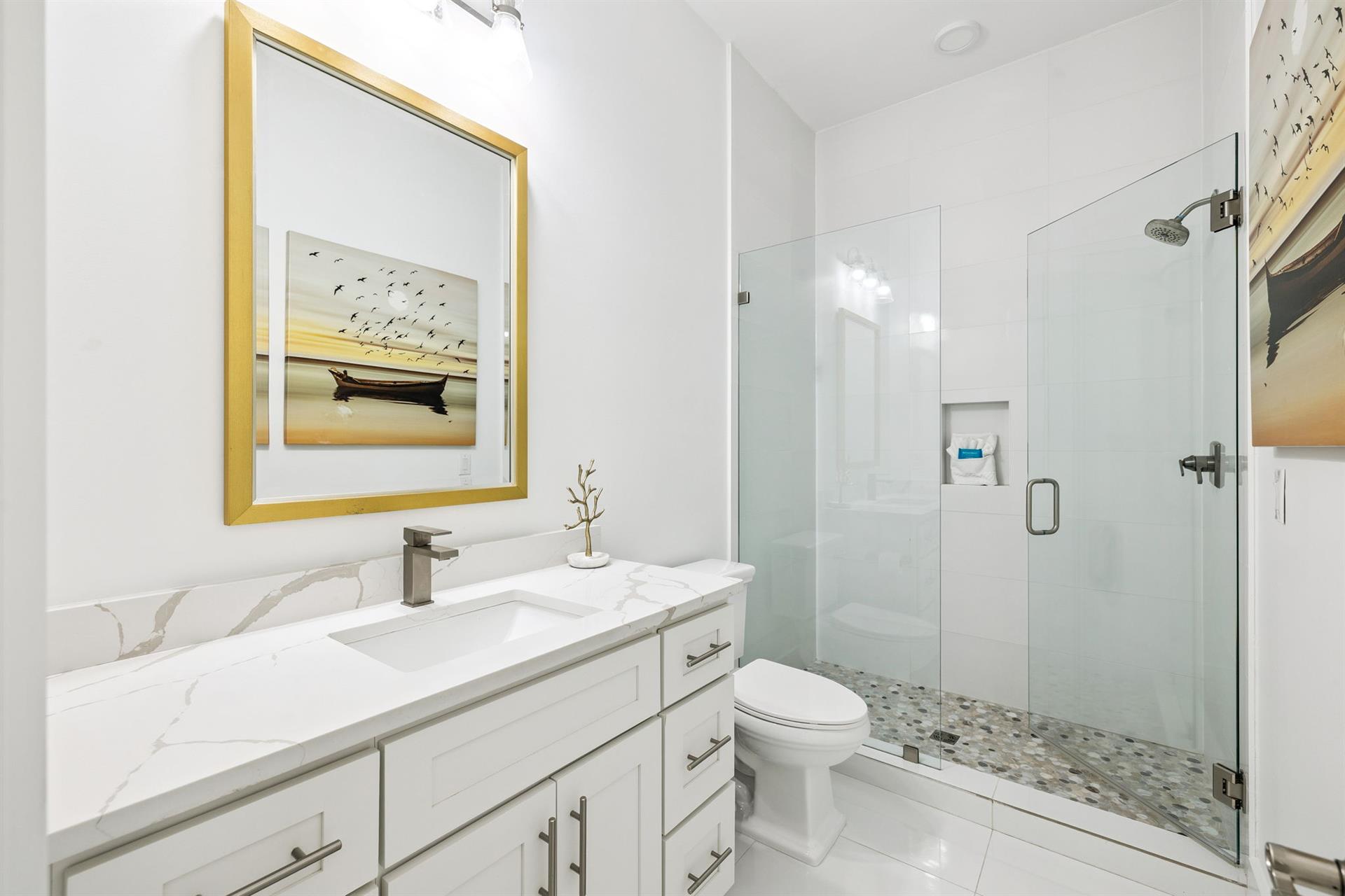 Pamper yourself in this pristine marble bathroom with elegant gold accents and a spacious glass shower.