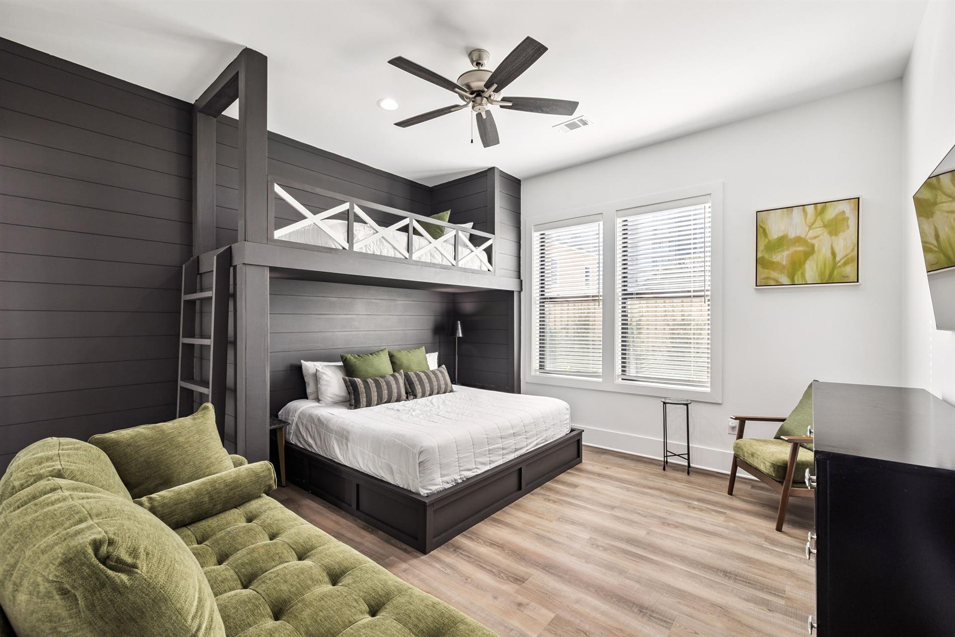 Your stylish bedroom features custom bunk beds, plush green seating, and modern comfort with a ceiling fan to keep you cool.
