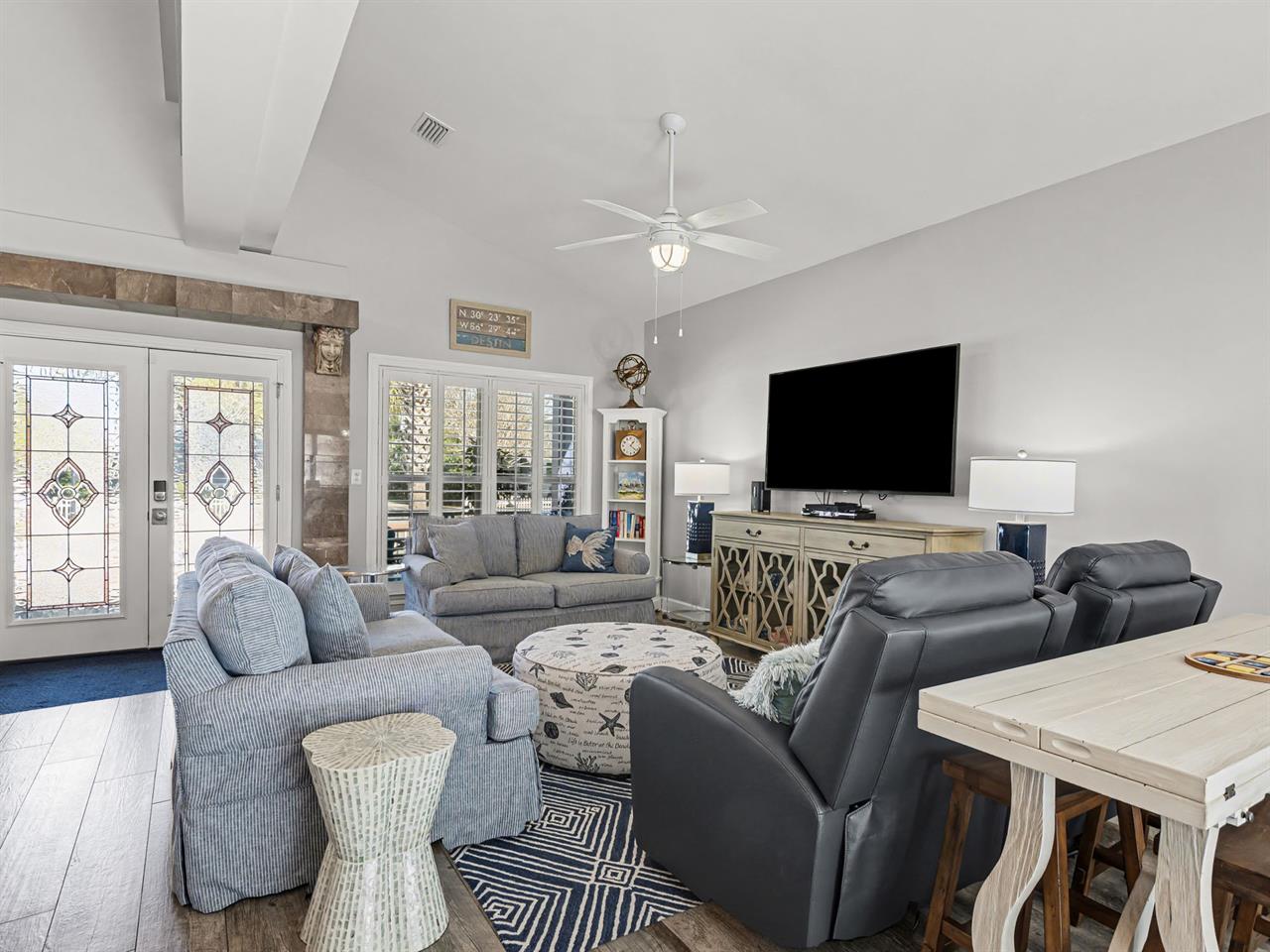 Relax in your spacious living room with plush seating, entertainment center, and rustic charm from exposed beams and stained glass doors.