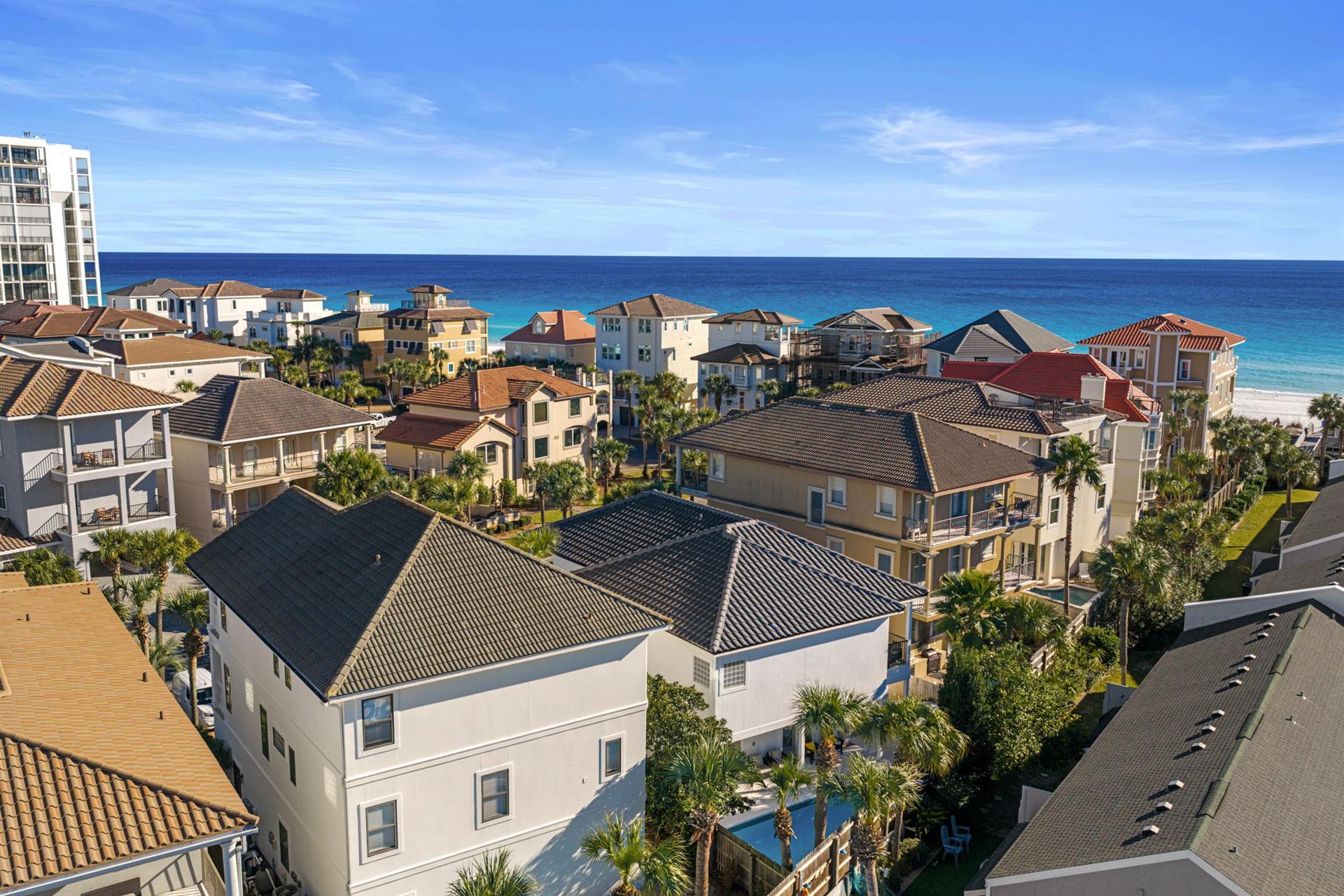 Coastal community overlooking pristine turquoise waters and white sand beaches, surrounded by tropical palm trees and residential buildings.