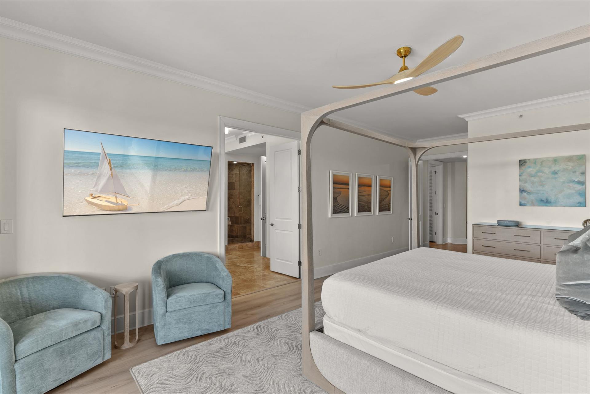 Your serene master bedroom features a canopy bed, coastal artwork, and cozy seating where you can unwind in sophisticated comfort.