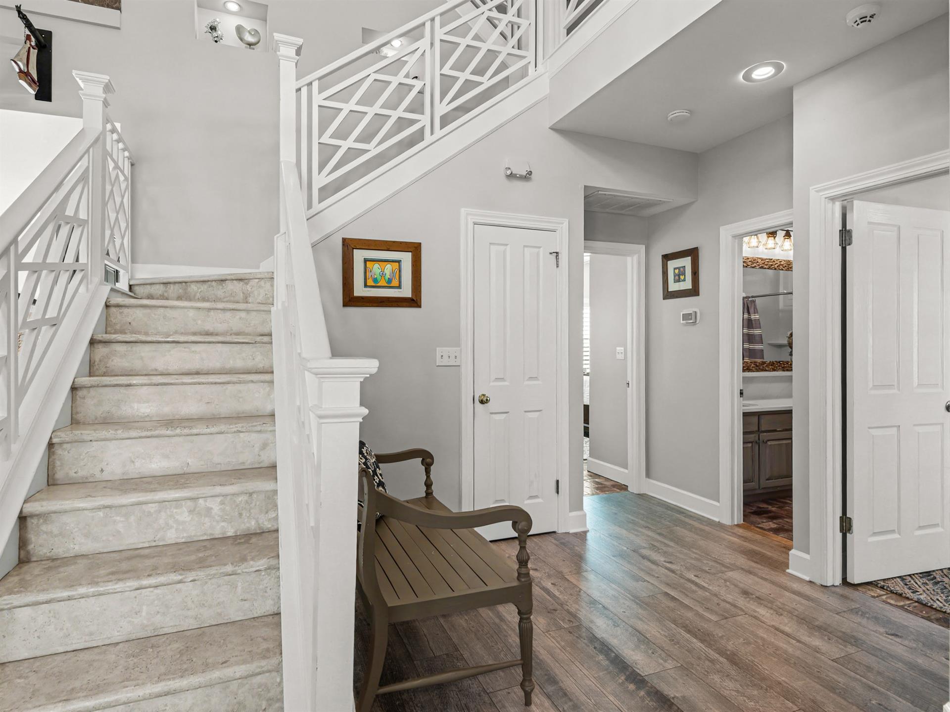 Step into your elegant entryway featuring rich hardwood floors, sophisticated gray walls, and a welcoming wooden bench where you can pause and settle in.