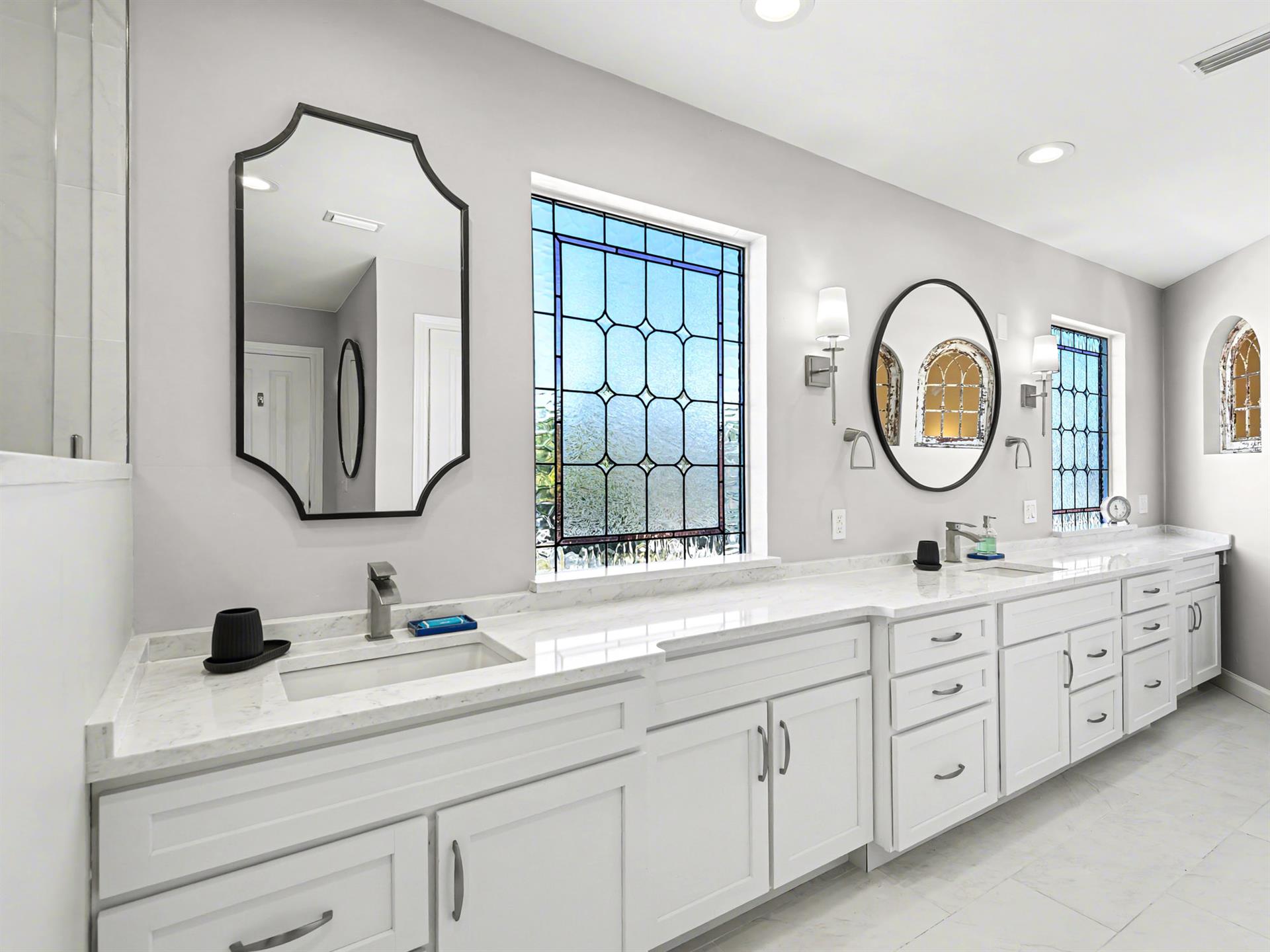 Pamper yourself in this stunning bathroom with dual vanities, marble countertops, and elegant mirrors perfect for your morning routine.