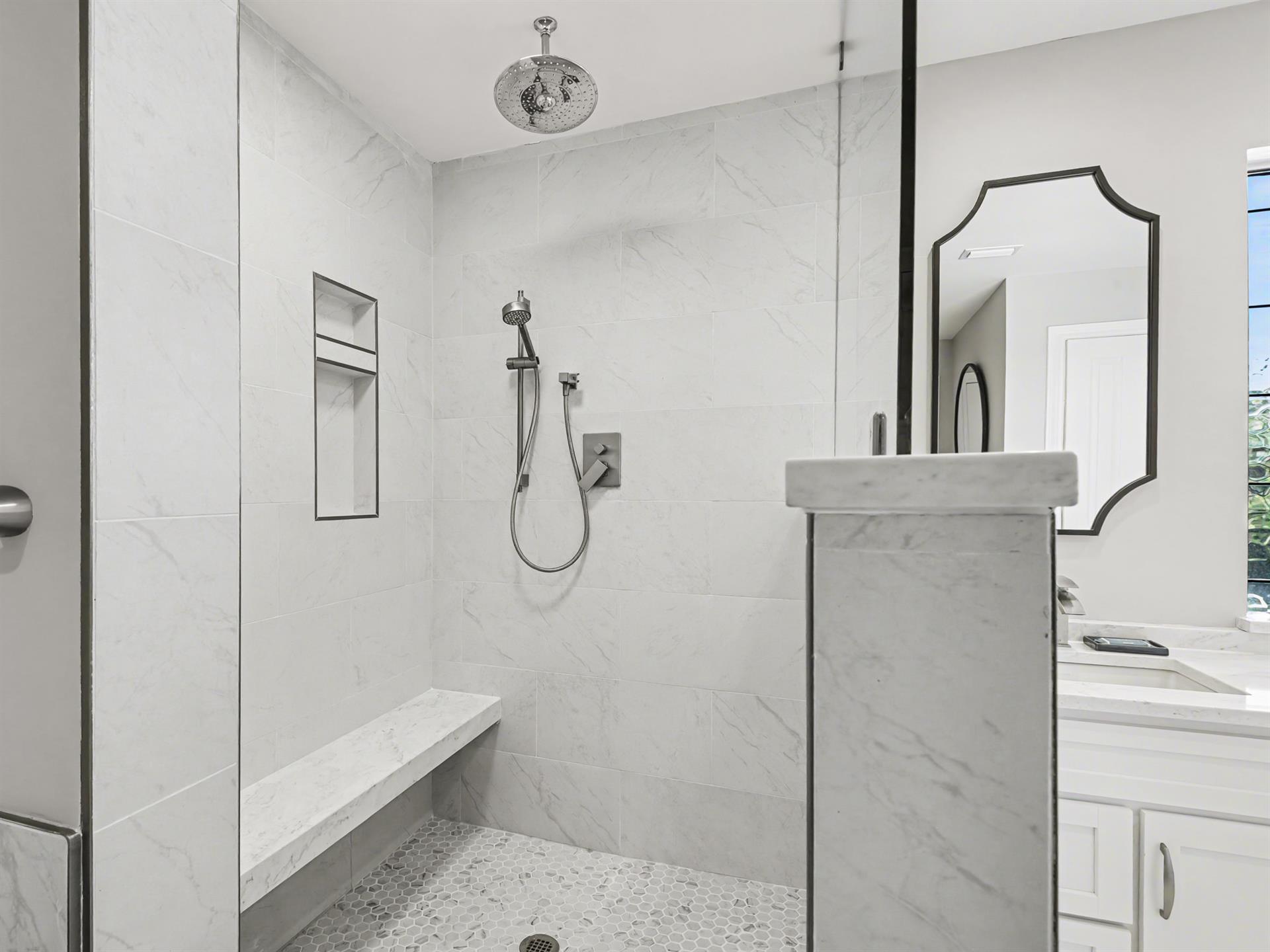 Step into your luxurious walkin shower featuring elegant marble walls, rainfall showerhead, and builtin bench for pure relaxation.