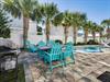 Your private backyard paradise features turquoise Adirondack chairs surrounding a sparkling pool, all framed by swaying palms under endless blue skies.