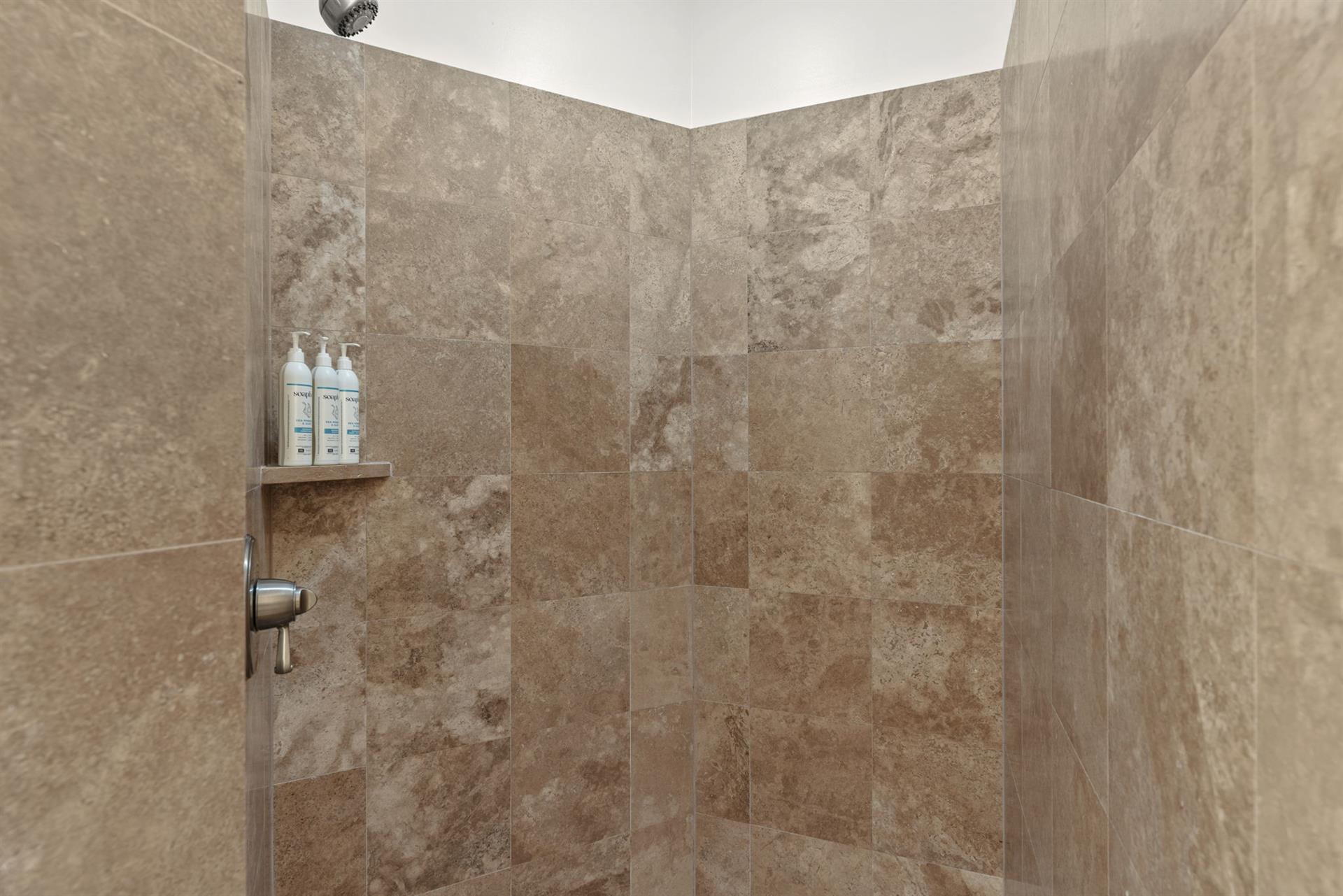 Step into your luxurious shower featuring elegant stone walls, rainfall showerhead, for a spalike experience.