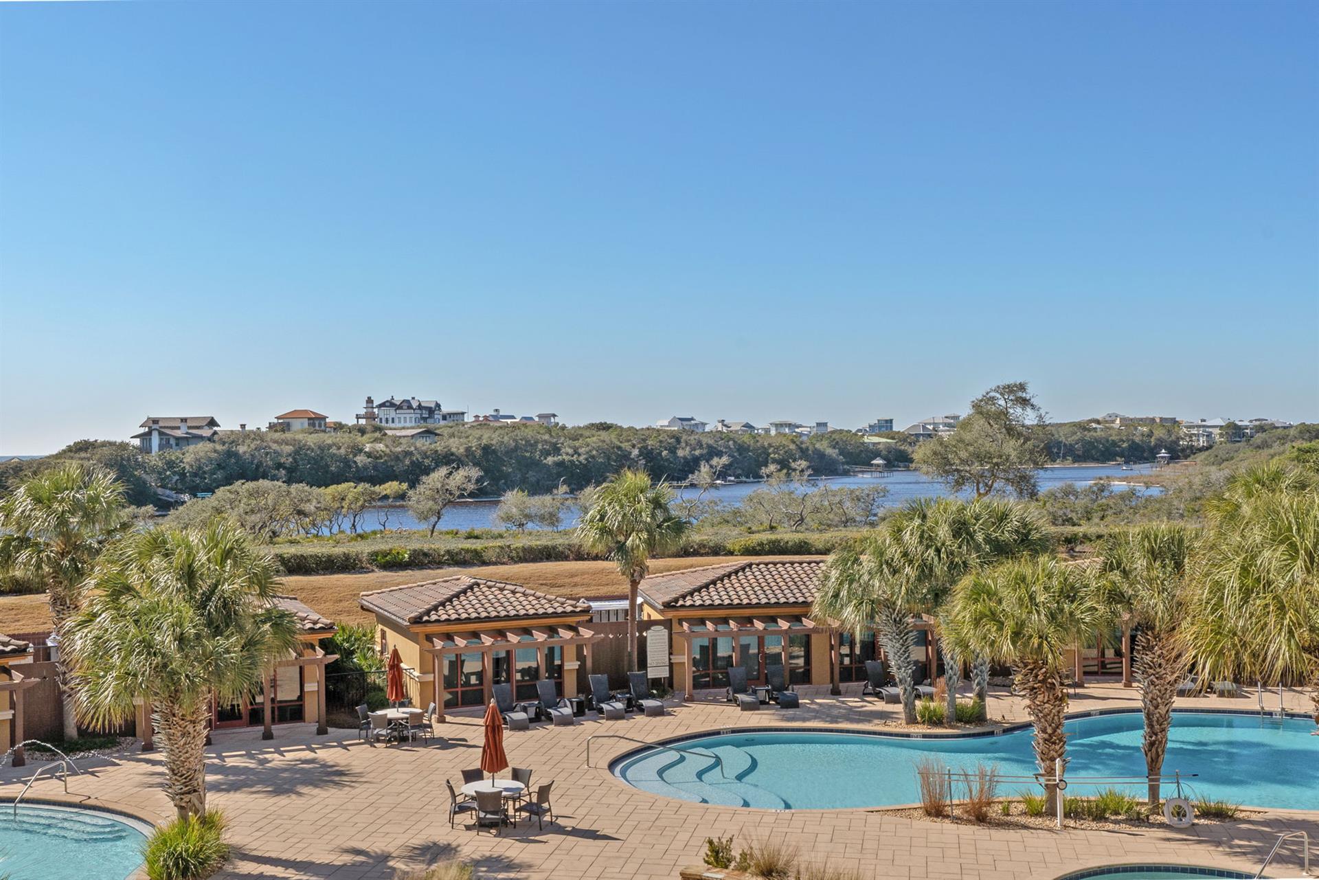 Spacious pool area featuring multiple swimming pools, hot tubs, and lush tropical landscaping with coastal views beyond.