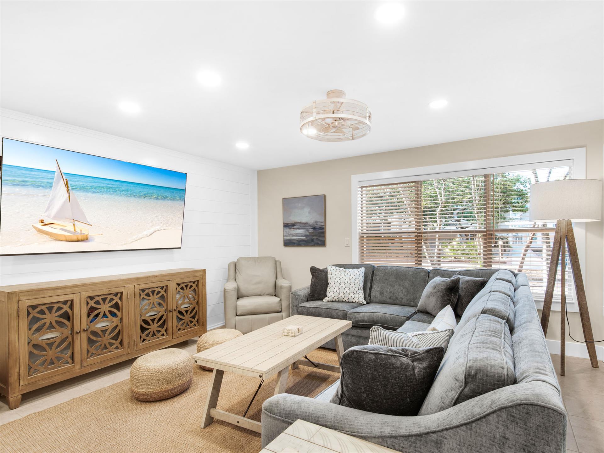 Coastalthemed living space with plush sectional seating and peaceful beach artwork setting the perfect vacation mood.