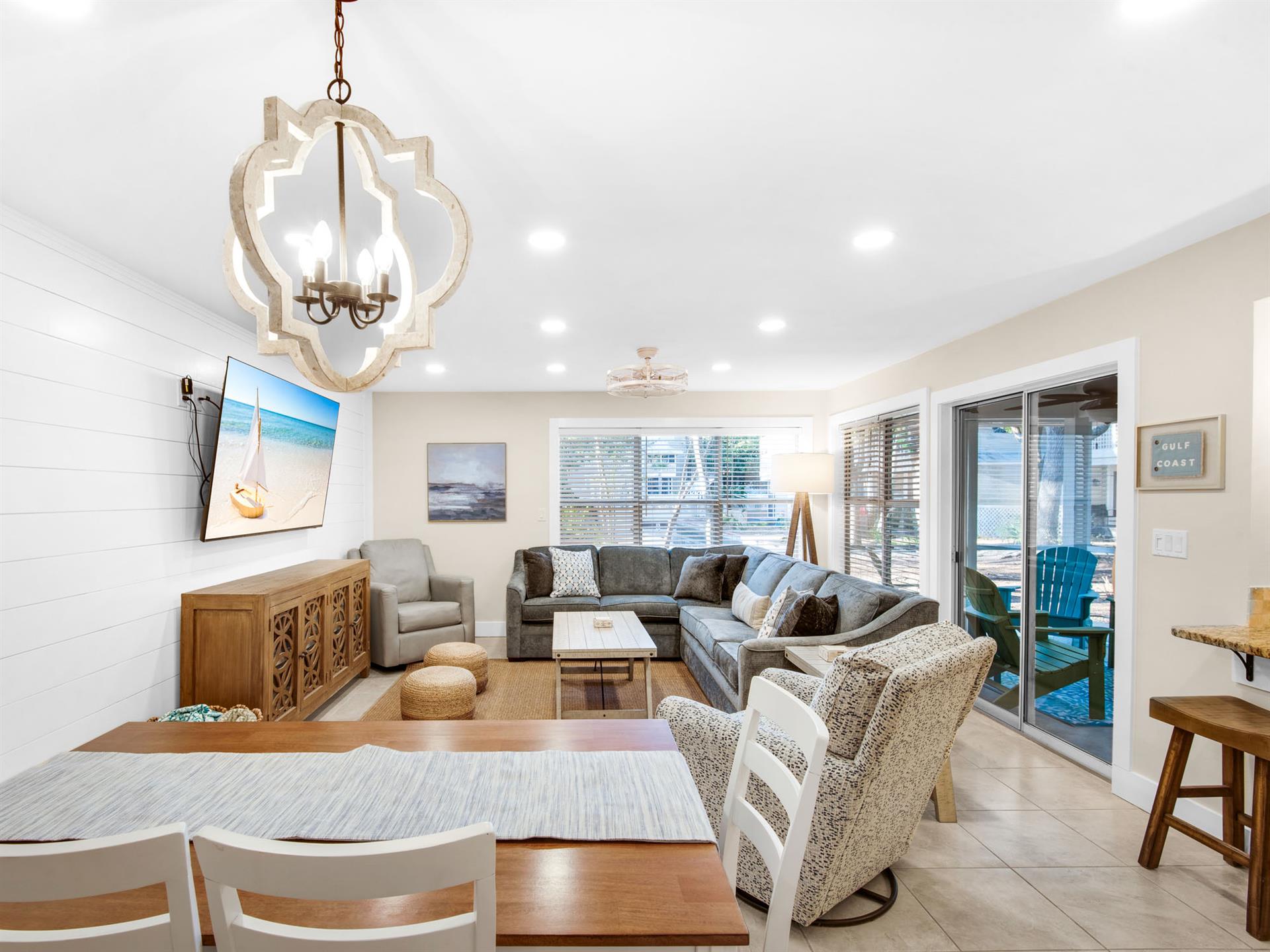 Relax in your beautifully appointed living room with plush sectional seating, elegant chandelier, and sliding doors opening to your screened porch