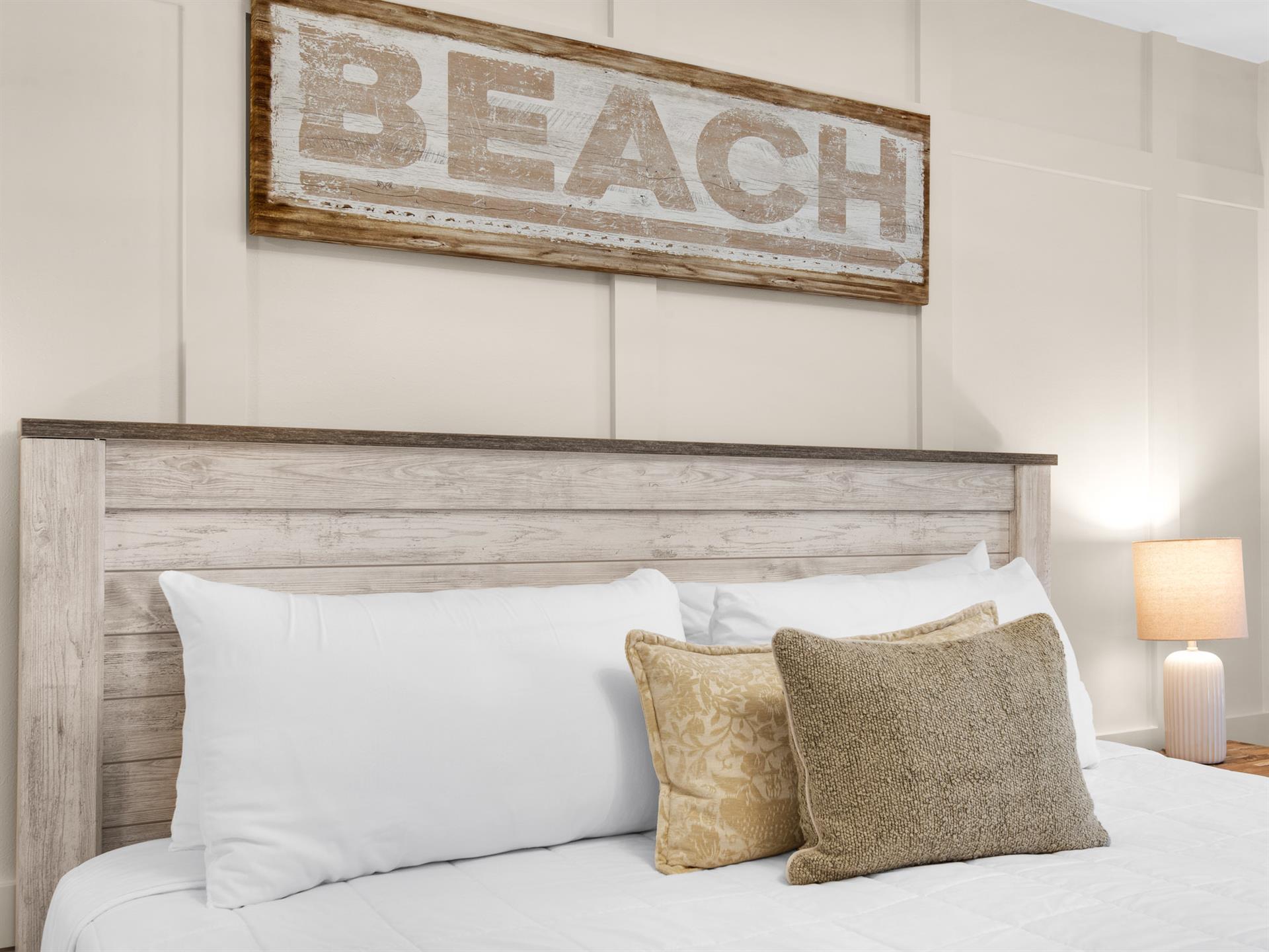 Sink into crisp white linens in your coastalinspired bedroom, where warm wood tones and beach decor create the perfect retreat.