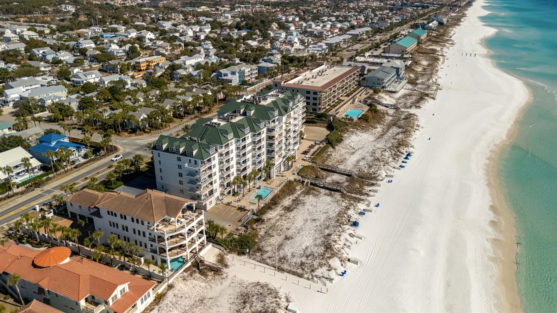 Beachfront resort community with pristine white sand beach and crystalclear turquoise waters stretching along the coastline.