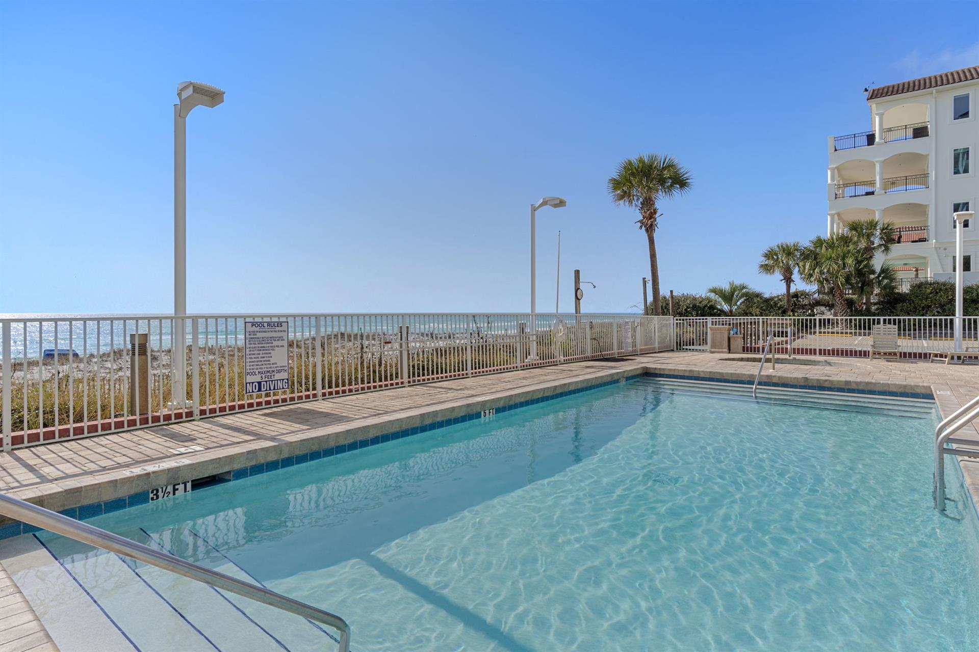 Crystalclear waters await in this gulf front community pool where palm trees sway and endless blue sky meets the horizon.