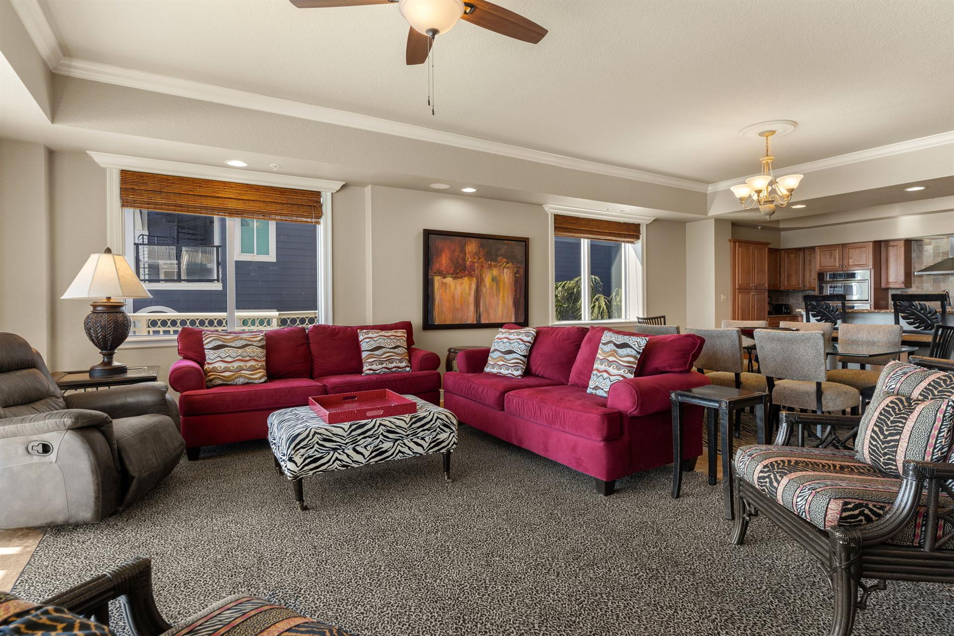 Sink into plush burgundy sofas in your spacious living room, where ceiling fans keep you cool and natural light streams through bamboo shades.