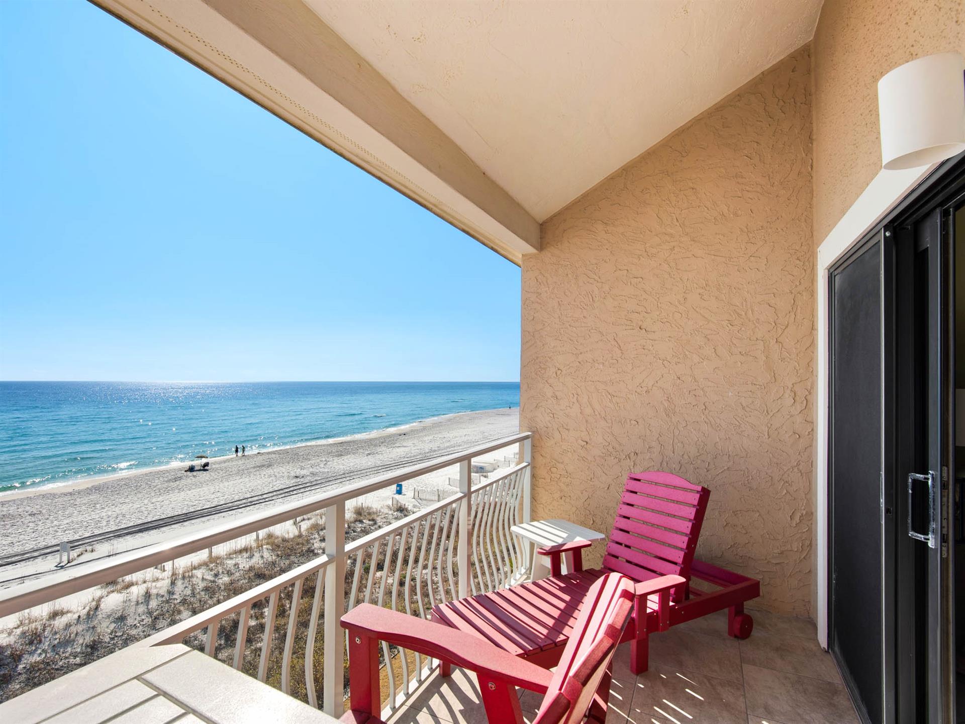 Wake up to stunning oceanfront views from the private balcony, where bright red chairs await your morning coffee and endless beach watching.