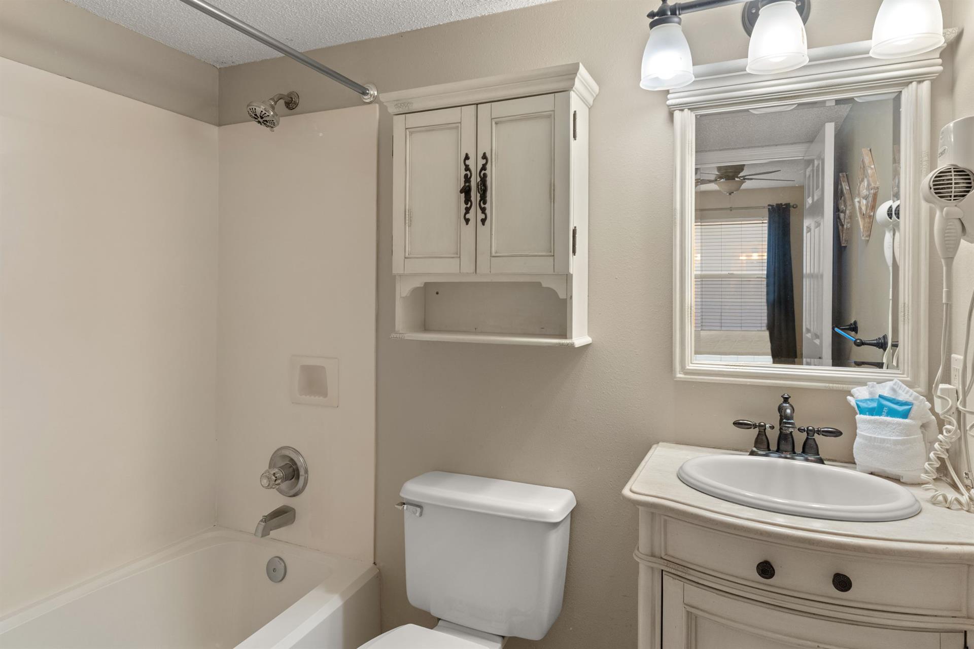 Bathroom 1 features a relaxing tub, modern vanity with mirror, and thoughtful storage to keep your essentials organized during your stay.
