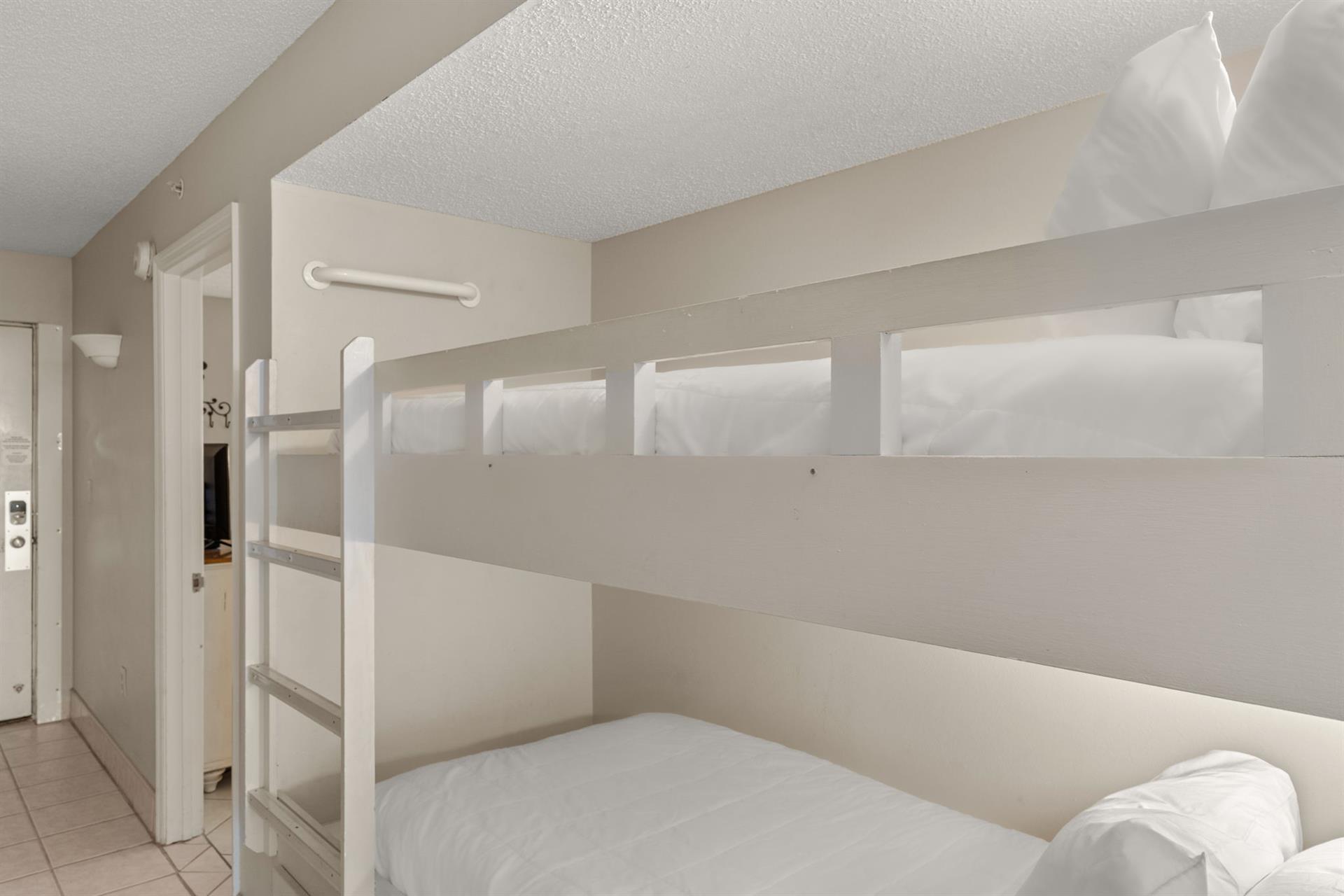 Cozy bunk bed space features crisp white linens and modern builtin design, perfect for restful nights.