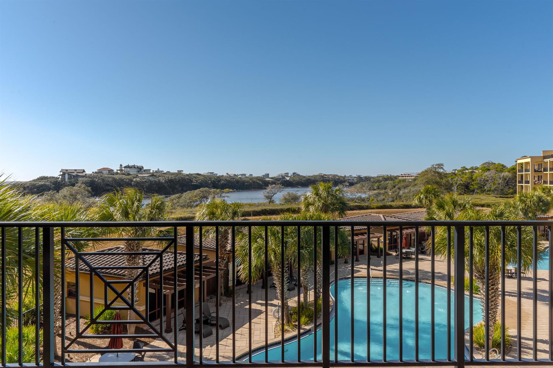 Wake up to this stunning vista from your balcony, where sparkling pool waters and lush tropical palms frame gulf and lake views.