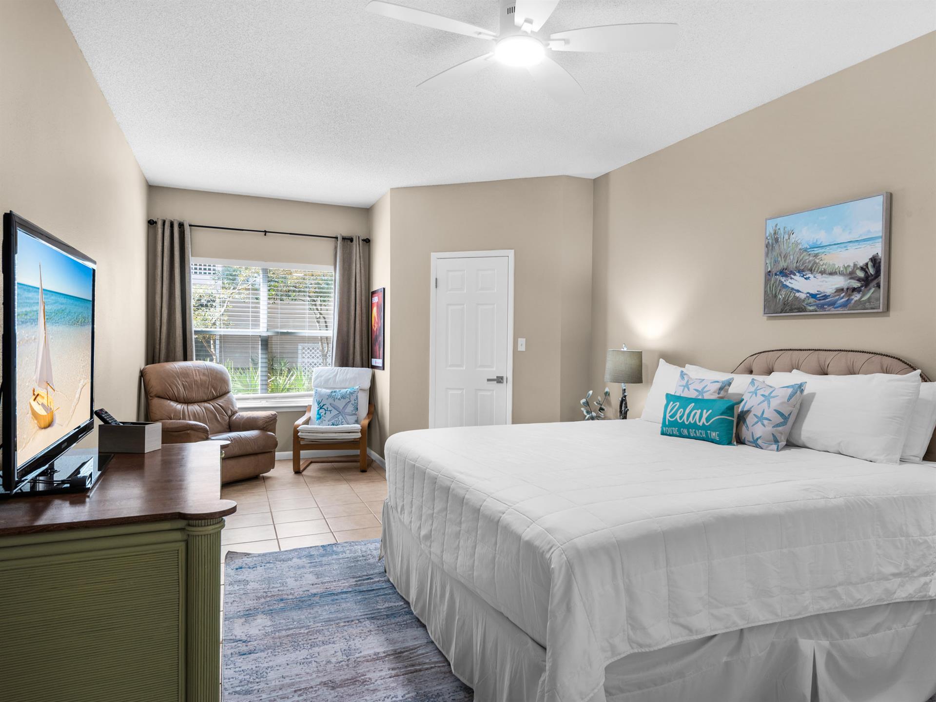 Unwind in your spacious bedroom with plush bedding, cozy seating area, and peaceful garden views through large windows.