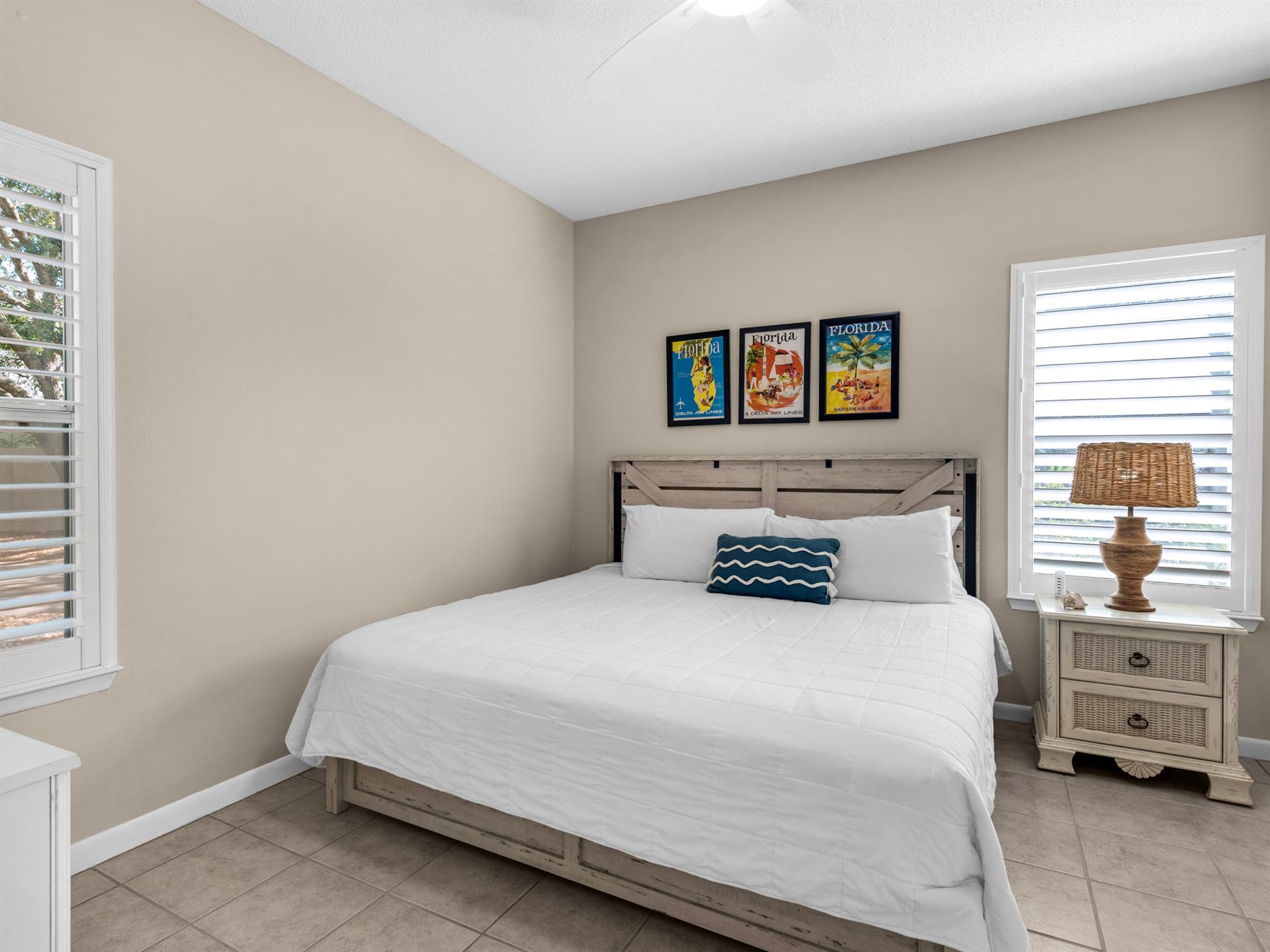 Drift into peaceful sleep in your coastalinspired bedroom with crisp linens and charming Florida artwork above the rustic headboard.