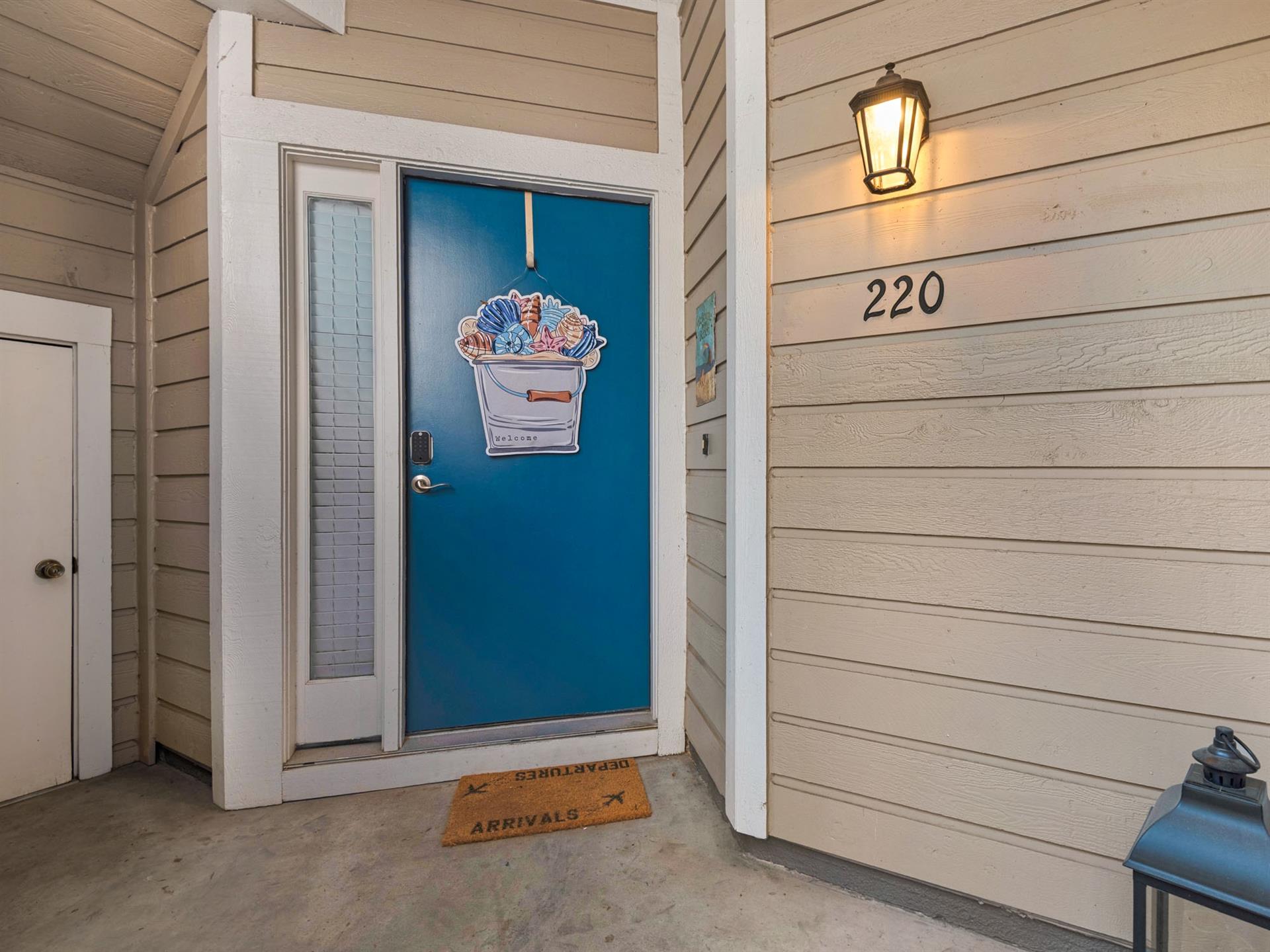 Property entrance with distinctive blue door featuring seaside artwork and unit number 220.