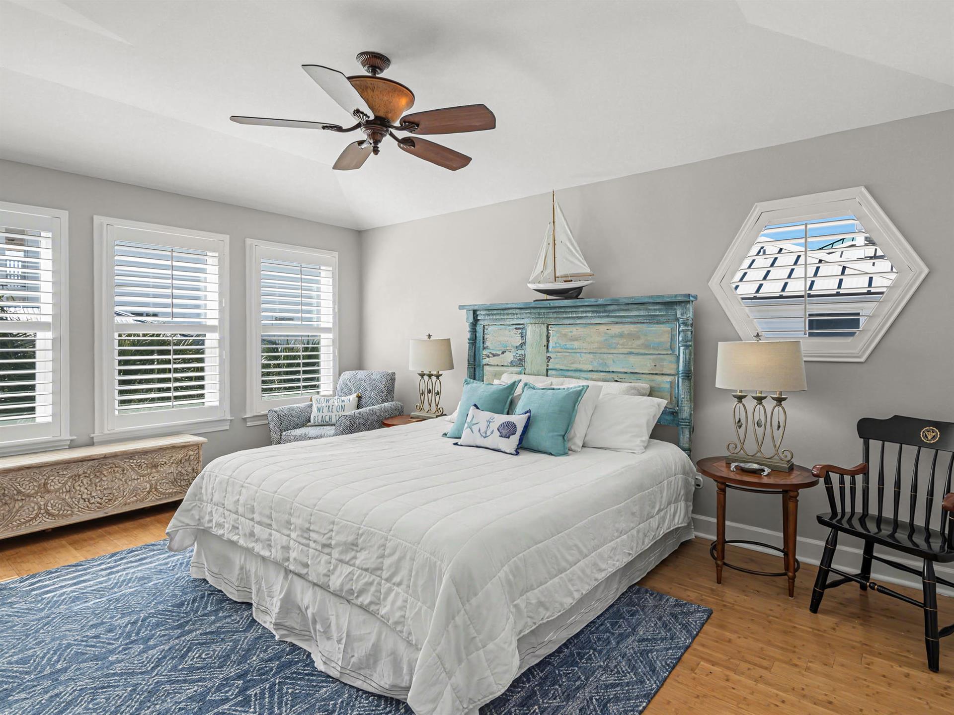 Drift off in this serene coastal bedroom with its weathered headboard, soothing teal accents, and gentle ceiling fan keeping you cool.