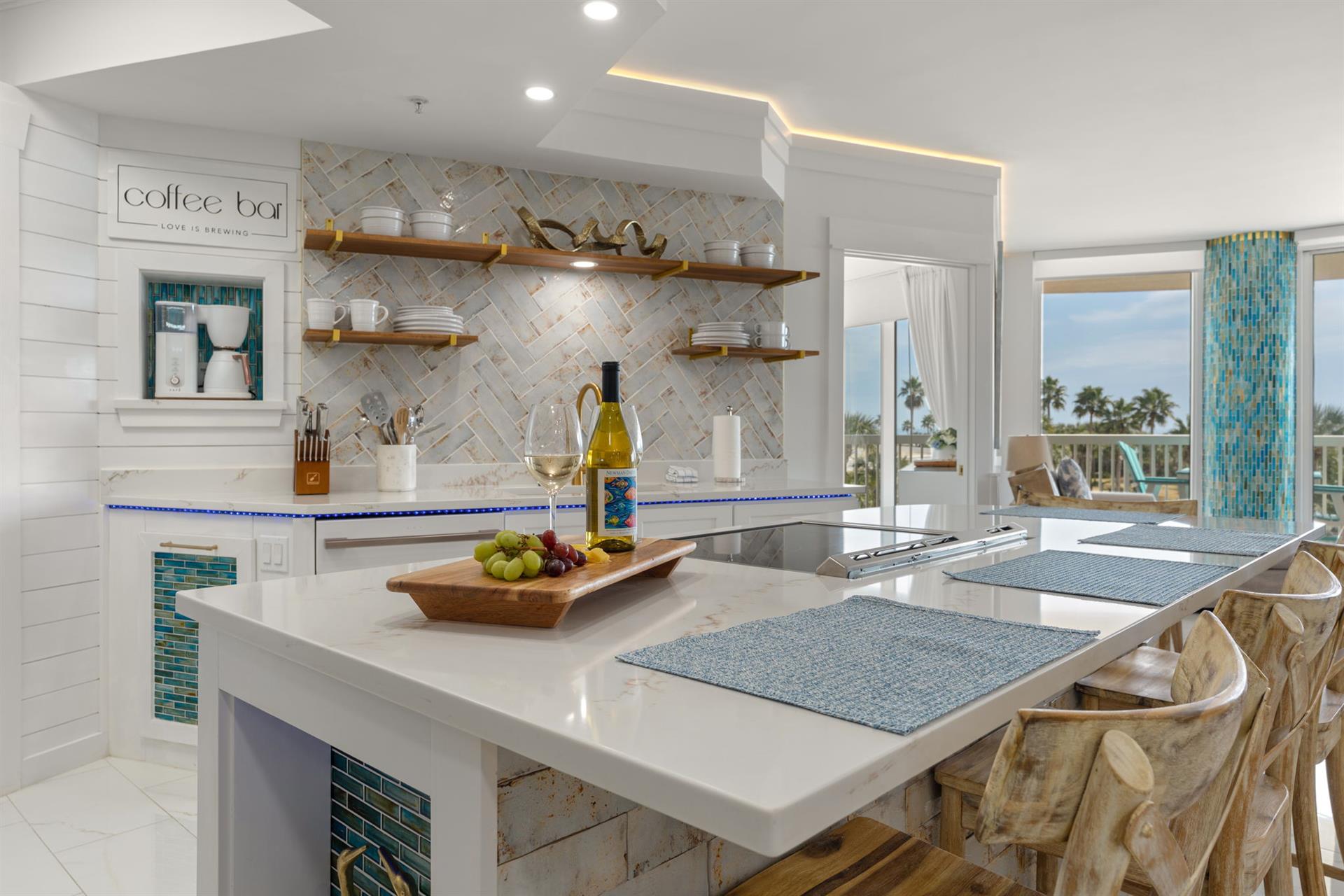 The gourmet kitchen awaits with sleek countertops, premium appliances, and tropical views through expansive windows.