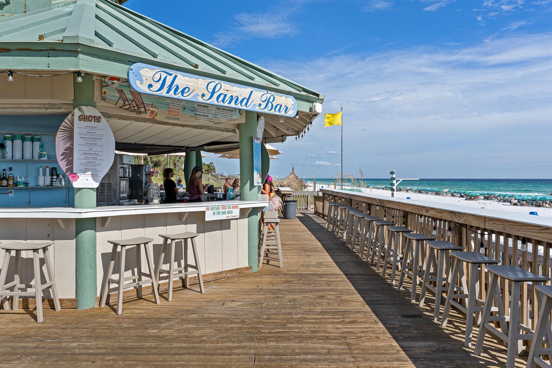 The Sand Bar offers refreshing drinks and stunning ocean views on this beachfront boardwalk, perfect for seaside relaxation.