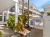 Tropical Caribbeanstyle property featuring white buildings with balconies surrounded by lush palm trees and colorful foliage.