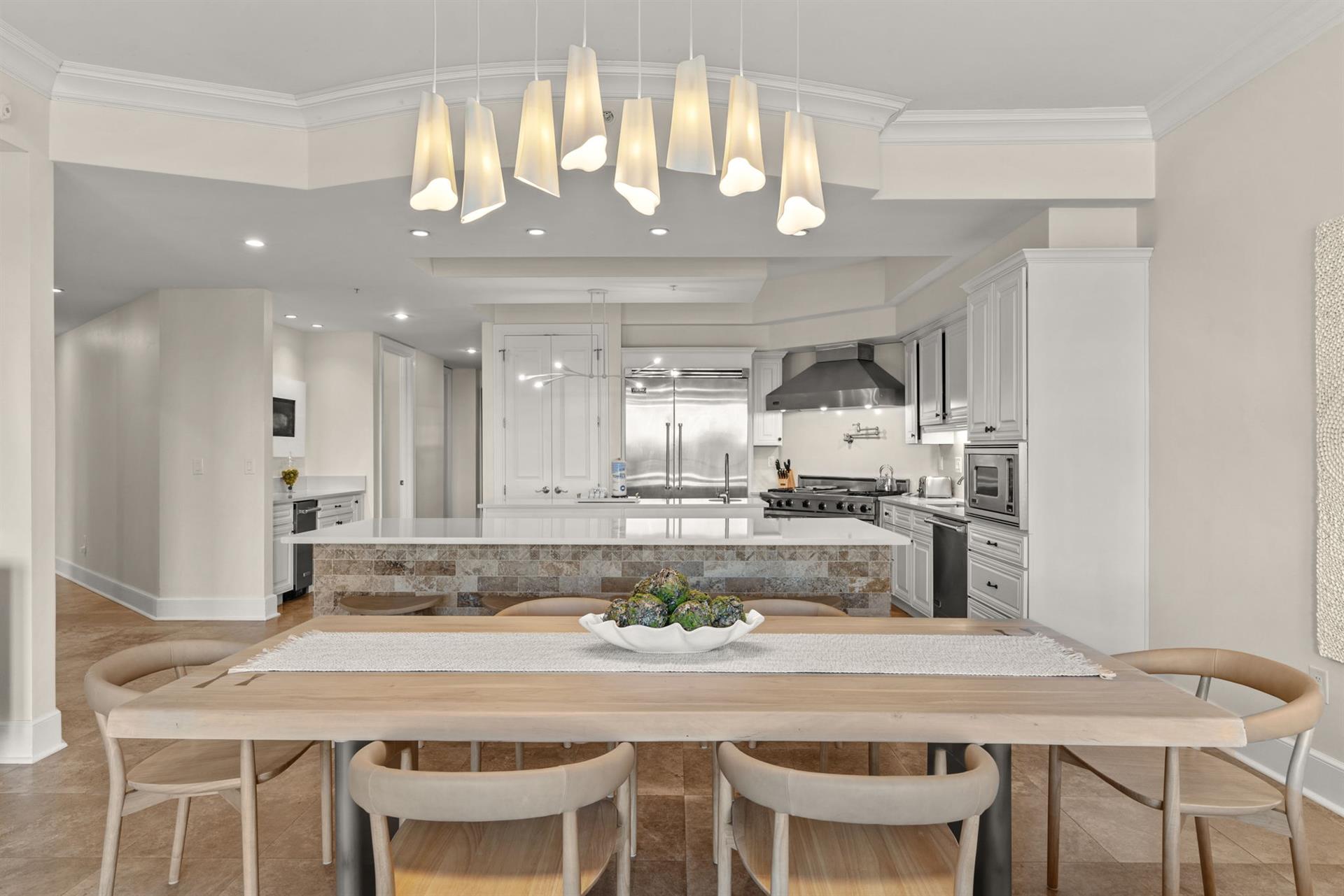 Your openconcept kitchen and dining space features elegant pendant lighting, modern appliances, and a warm wood table perfect for memorable meals.